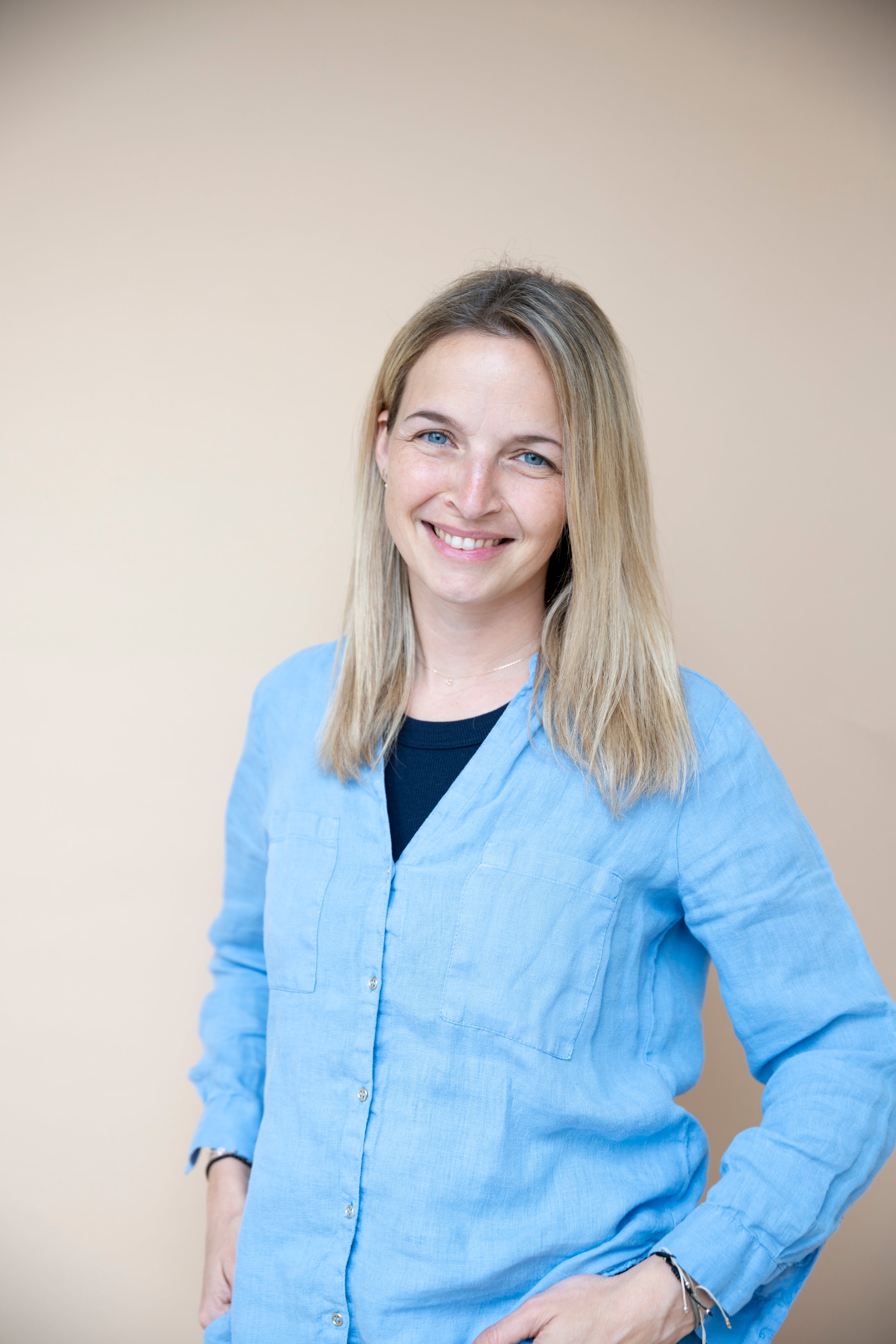 midage woman with blue shirt posing in front of brown background, business portrait