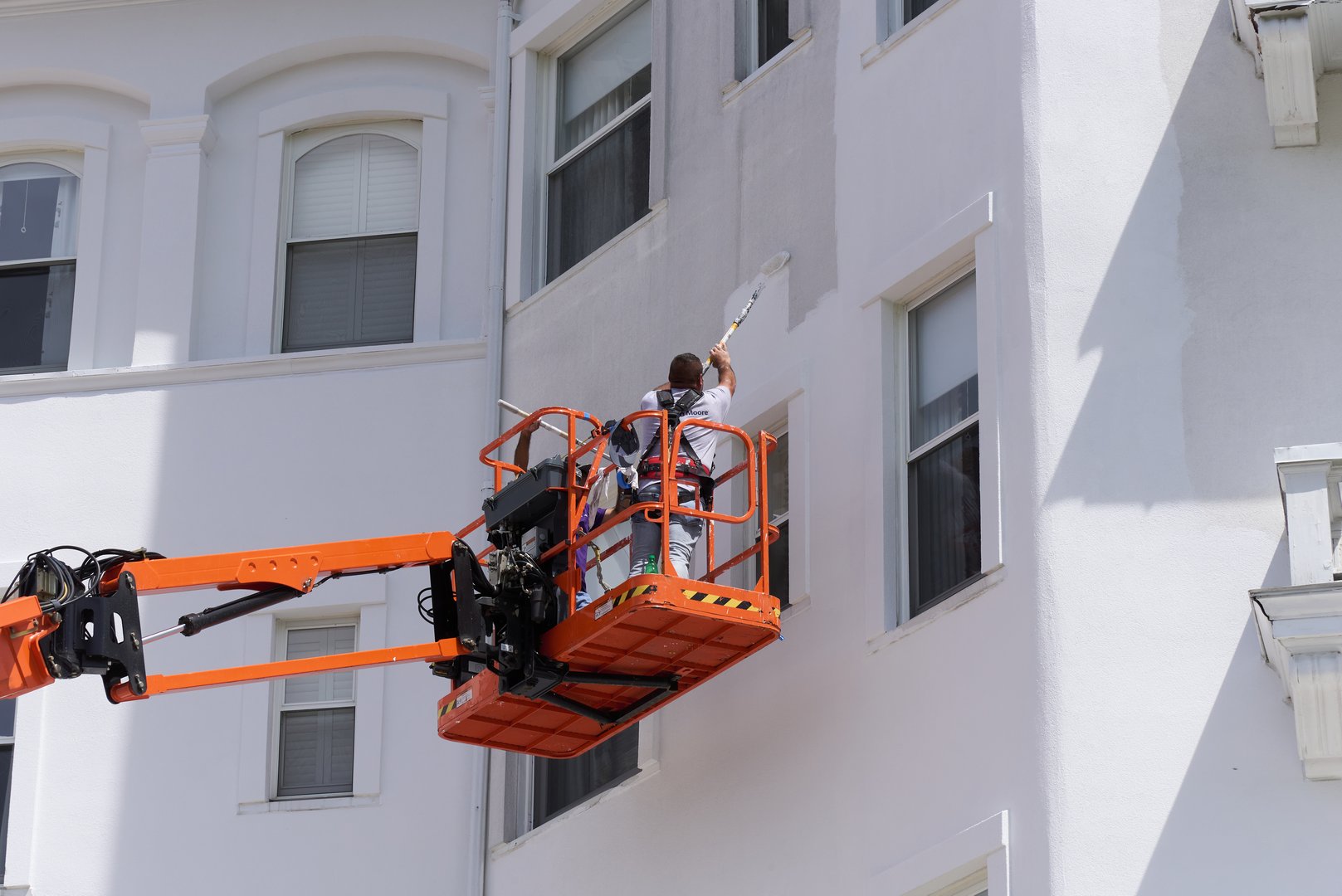 Carroll, NH USA - August 3, 2022: Painting the Omni Mt Washington Hotel. A man on a boom lift uses a roller to apply white paint to the facade of the building in Bretton Woods, NH in the White Mountains.