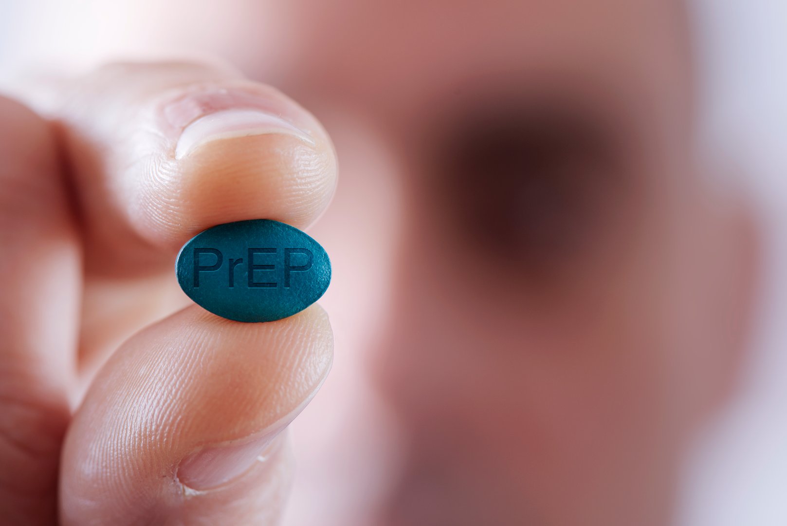 closeup of a young caucasian man with a simulated PrEP pill in his hand