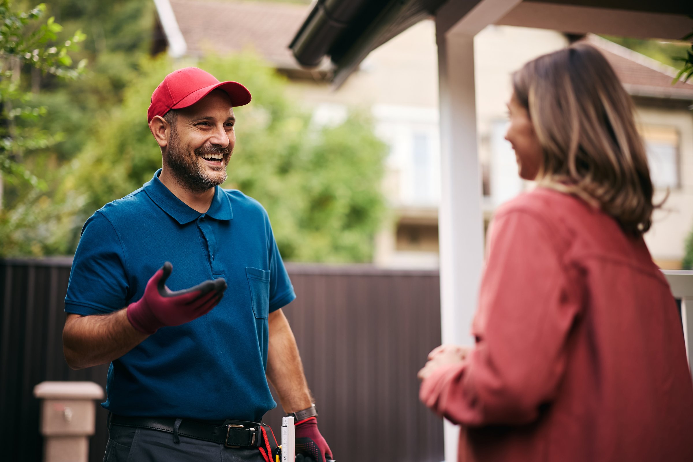 Happy handyman talking to female client in the backyard.