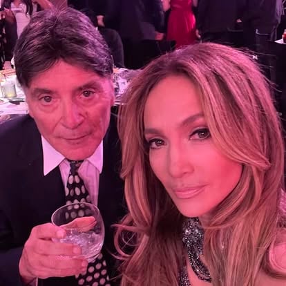 Two people at an event; one holding a drink, both looking at the camera.