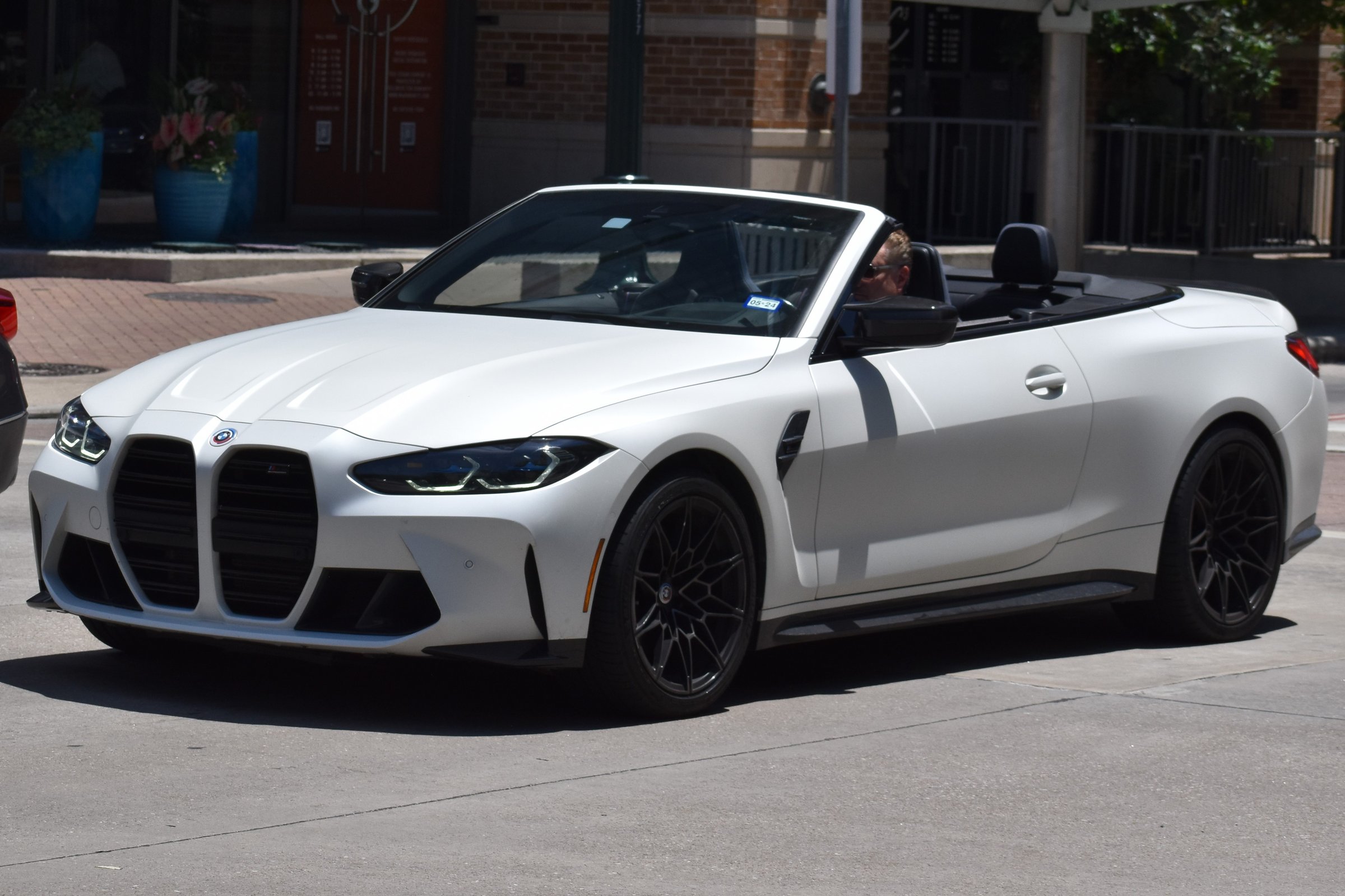 Houston, TX USA - 5-15-2024 - A portrait of a black and white BMW M4 convertible cruising in a downtown district