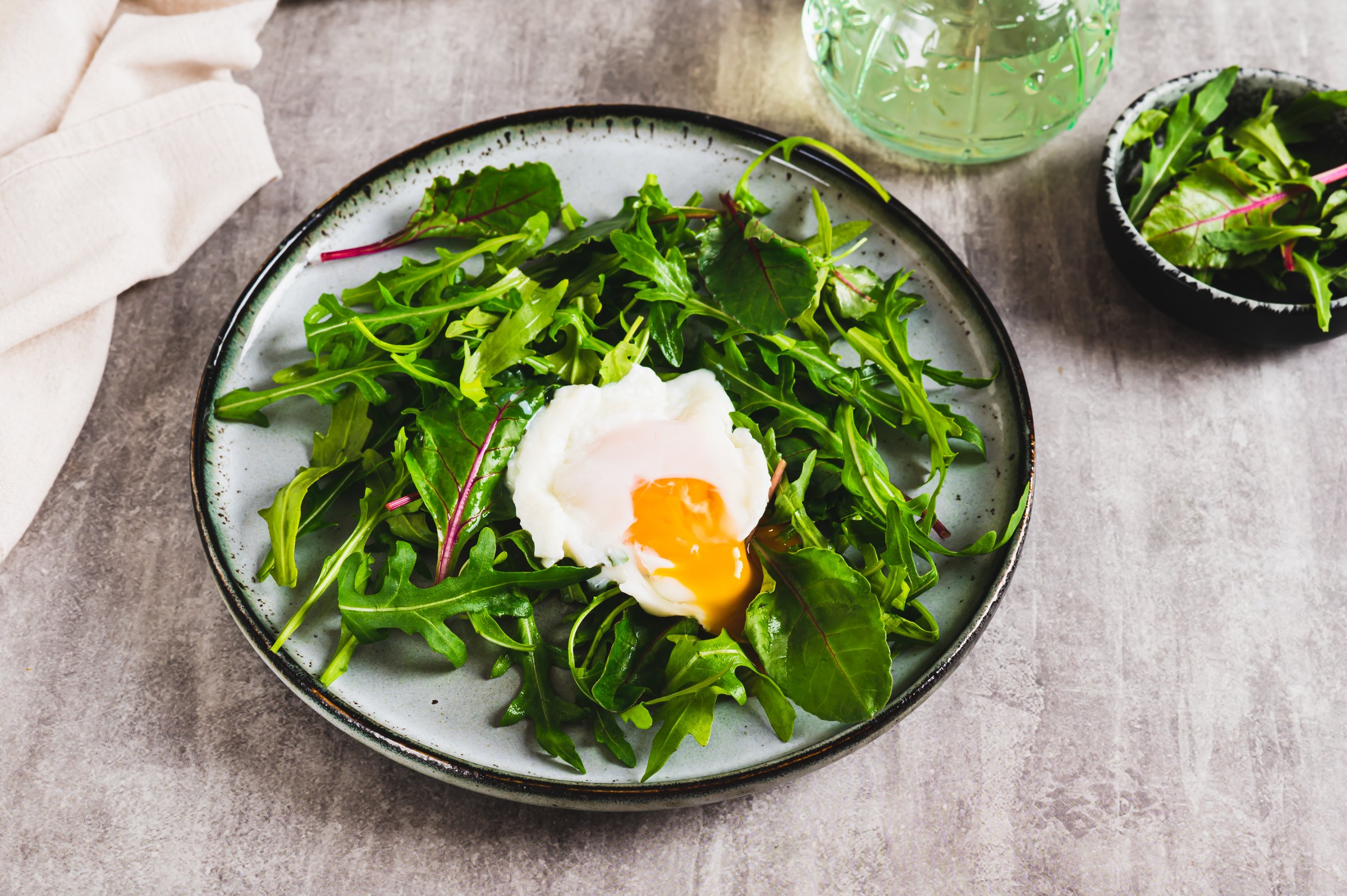 Leafy greens and poached egg on a plate on a table