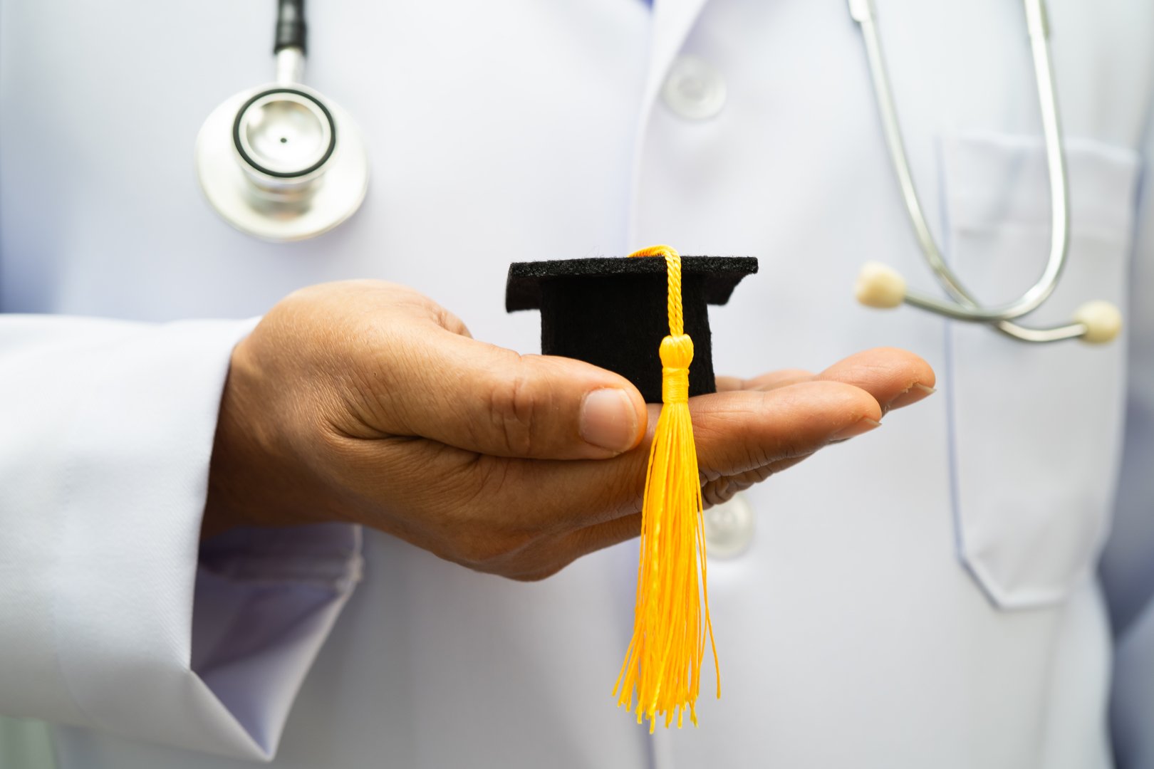 Asian woman doctor holding graduation hat in hospital, Medical education.