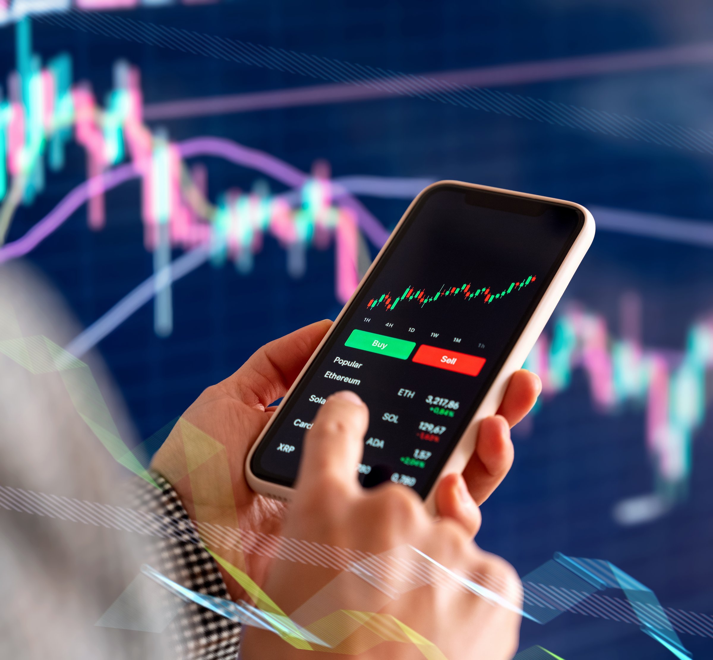 Trader using smartphone with crypto trading app and financial charts in front of large digital screen. TradingView platform
