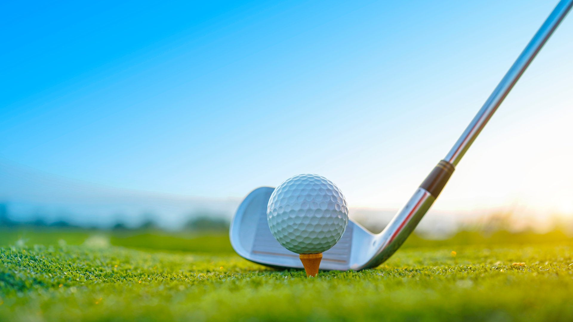 Golf clubs and golf balls on a green lawn in a beautiful golf course with morning sunshine. Close up of golf equipment on green grass.