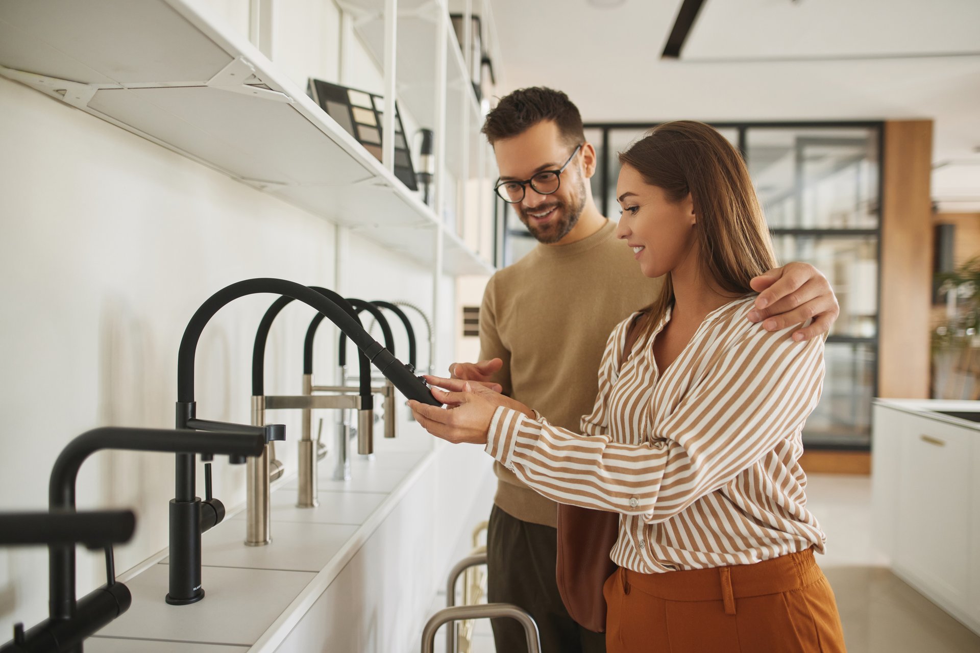 Couple choosing new sink faucet for their home in modern appliances store