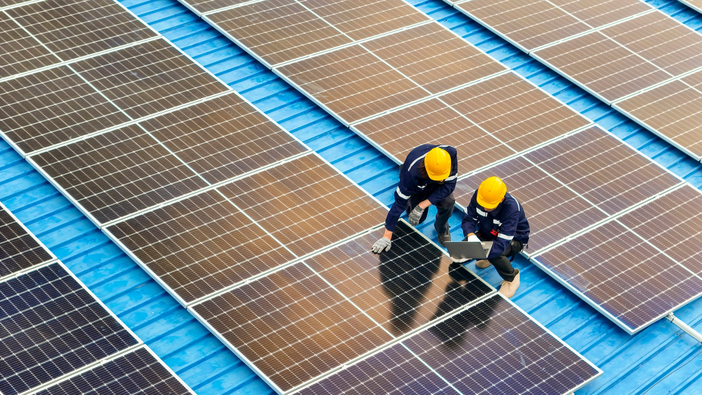 Photovoltaic engineers work on roof top warehouse. workers Inspect and repair the solar panel equipment roof structural. Engineer working set up electrical renewable energy for sustainability.