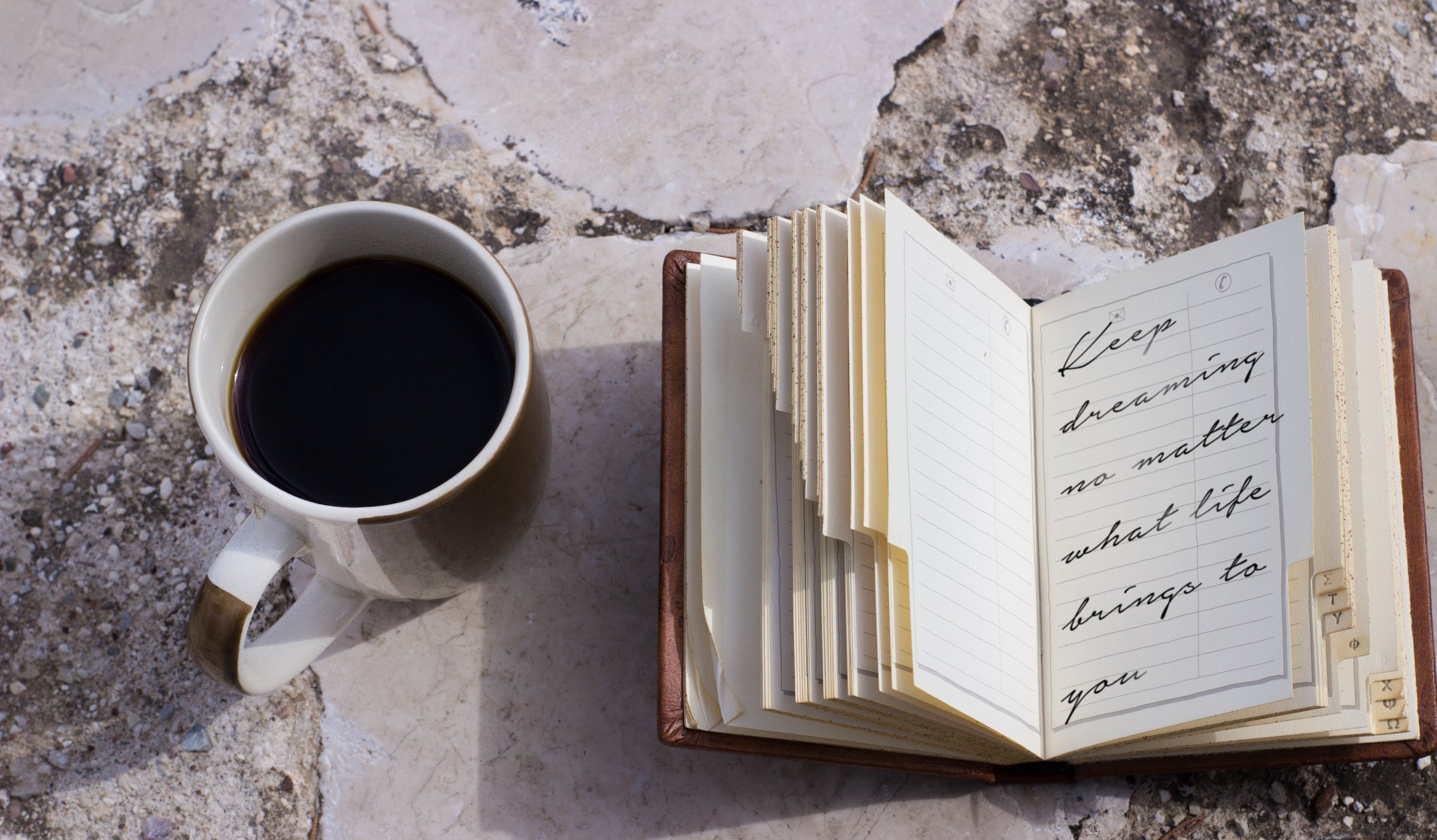 coffee mug and a small notebook with handwritten text about following your dreams diary