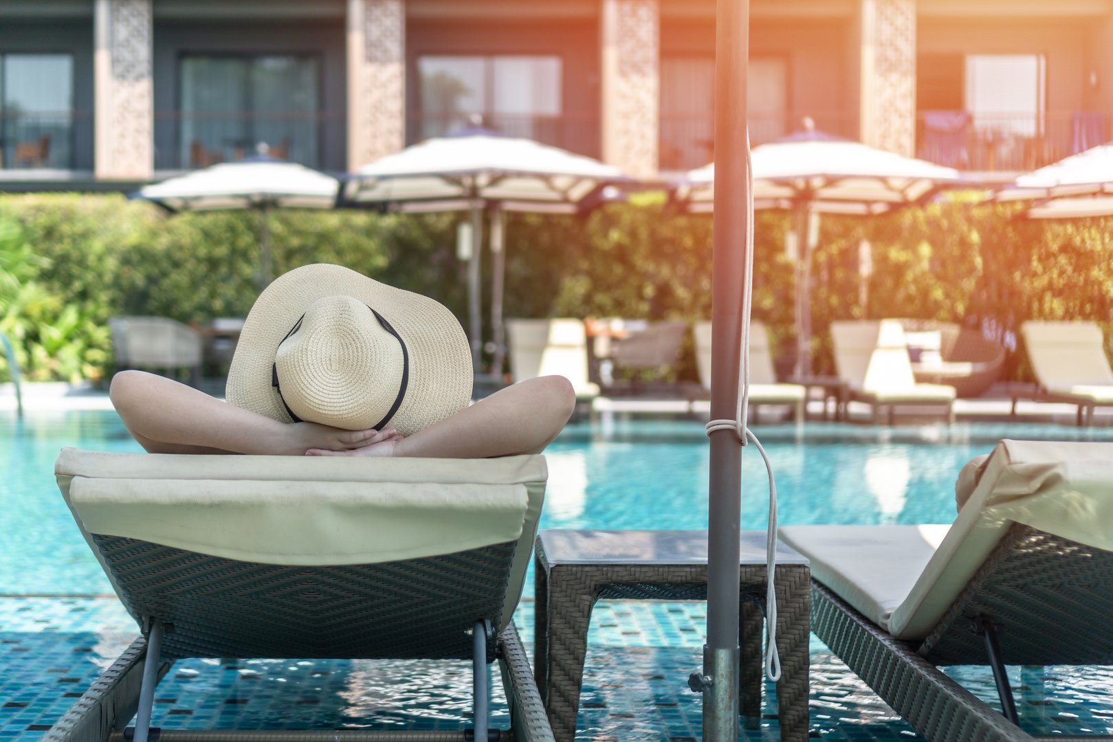 Holiday relaxation Summer vacation of woman take it easy, happy life quality, resting on beach chair at swimming pool poolside beachfront with resort hotel view background