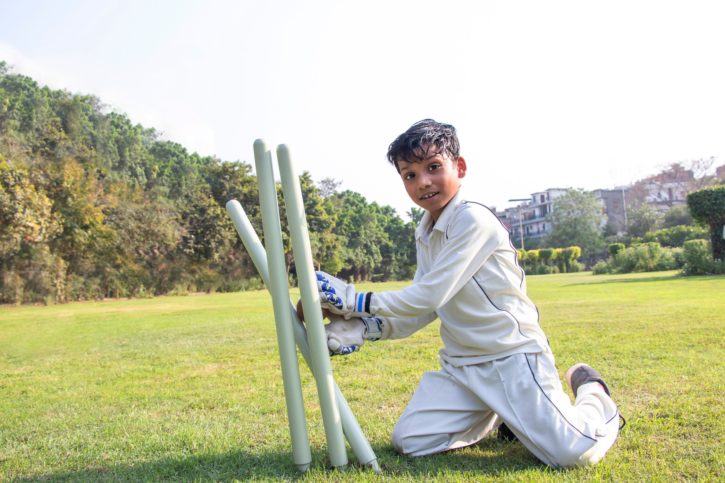 a boy fielding on the ground during cricket game
