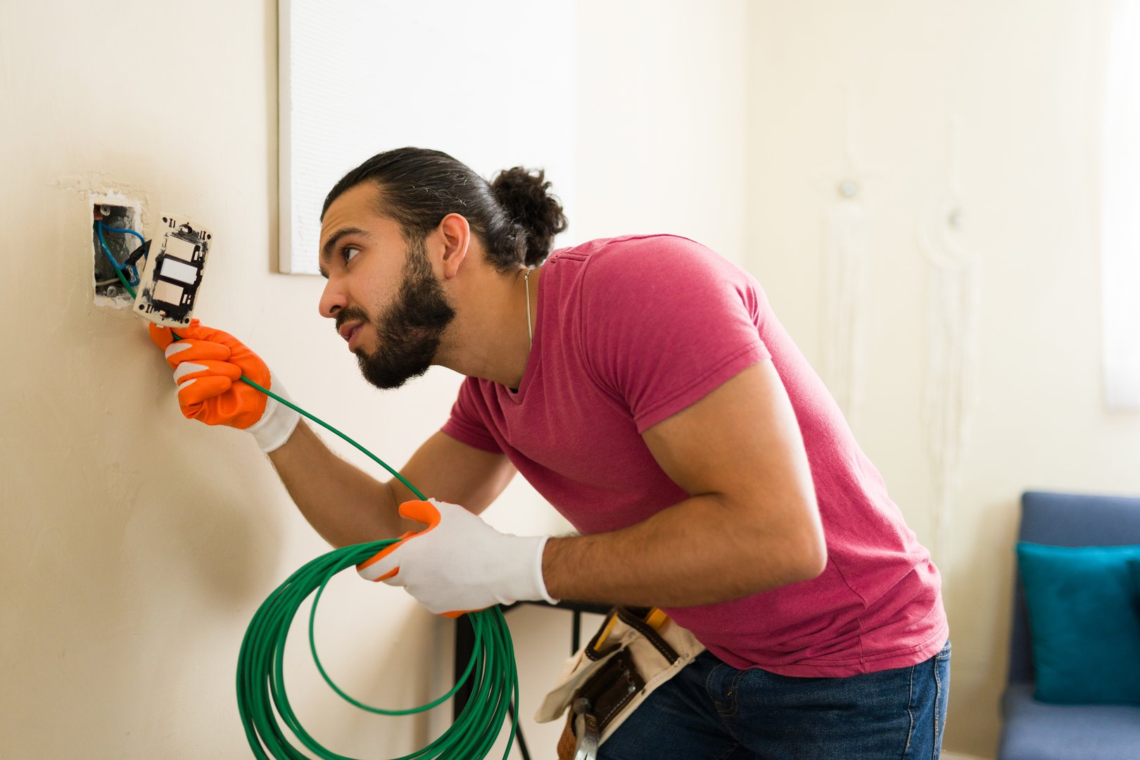 Professional electrician carefully installing a light switch and connecting the electrical cable in a residential building, ensuring proper wiring and functionality