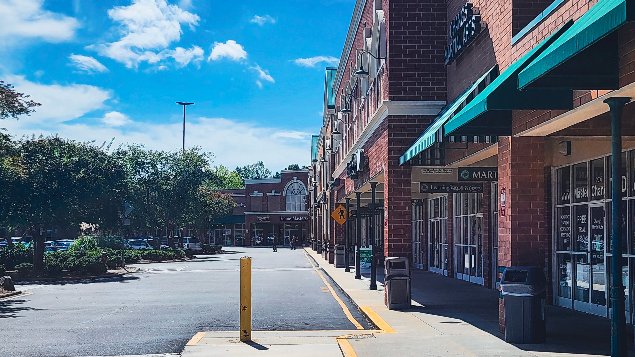 Editorial stock photo of shopping center in Cary, North Carolina, with retail stores and outdoor walkway captured on a sunny day. Shopping center near Walmart in Cary, North Carolina, USA