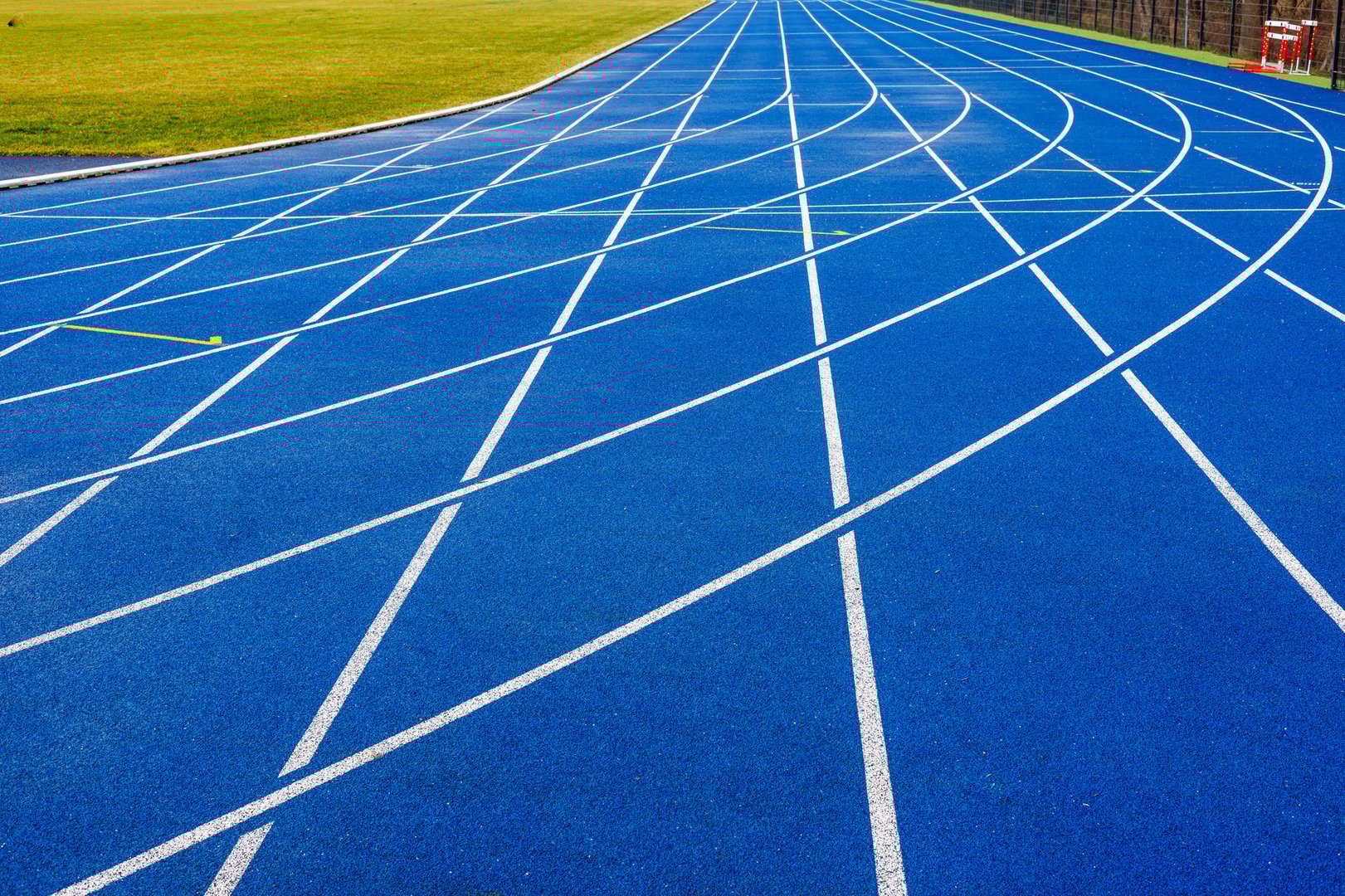 Blue running track at the new stadium, next to the artificial green turf. Turning the running tracks. High quality photo
