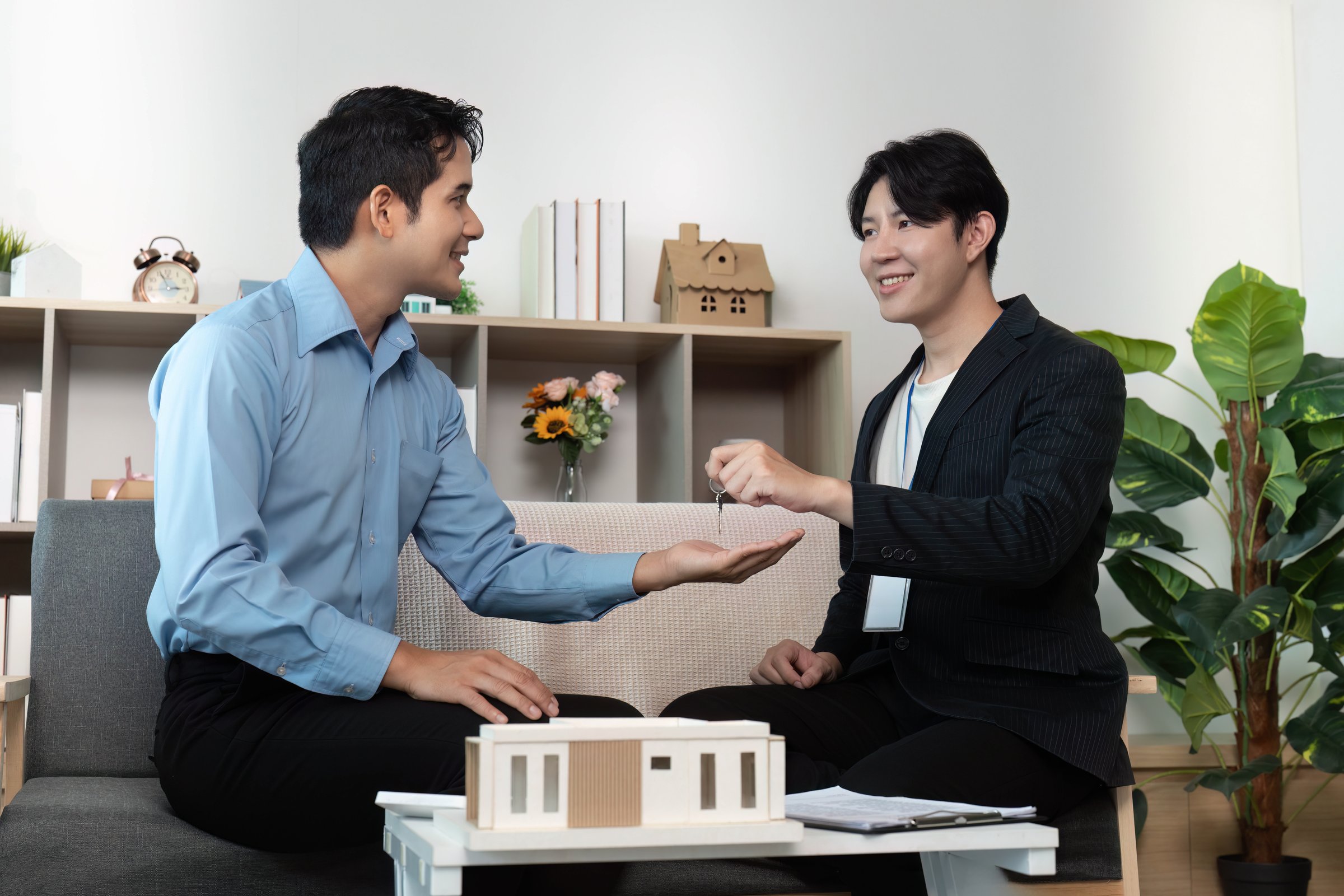 A real estate agent presents keys to a client, symbolizing a successful property transaction in a stylish interior.