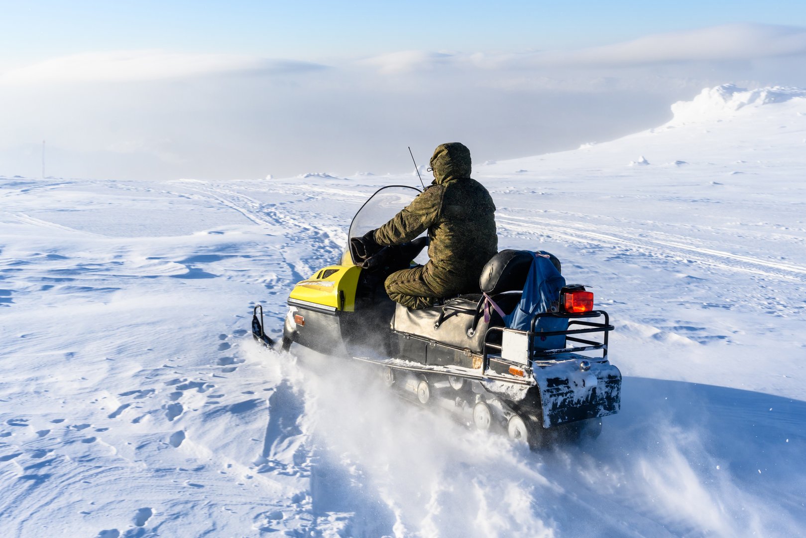 A man is riding snowmobile in mountains. A panoramic view of the covered with snow trees in the snowdrifts. Magical winter forest. Nature winter landscape.