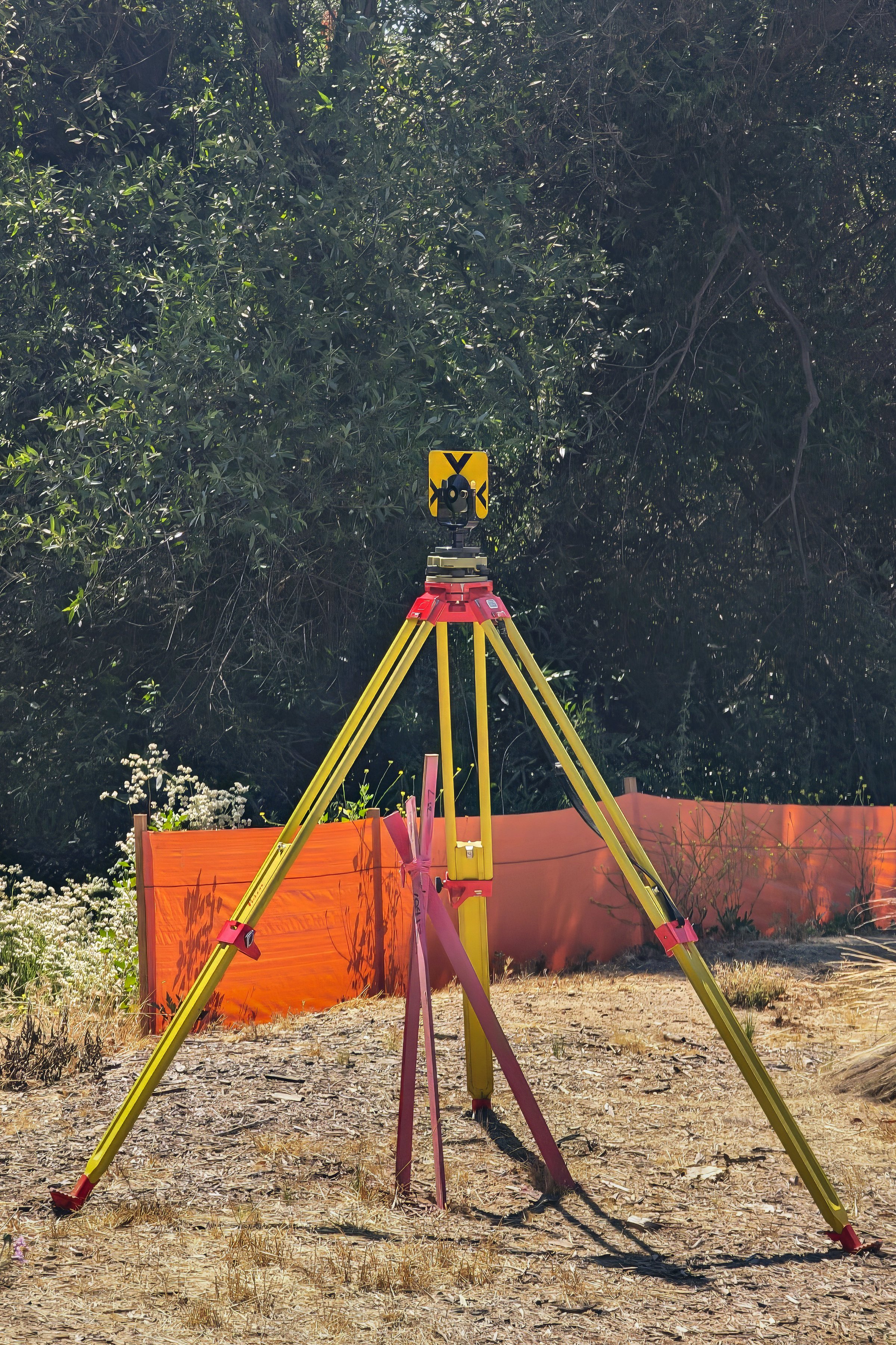Surveyor equipment on tripod at construction site.