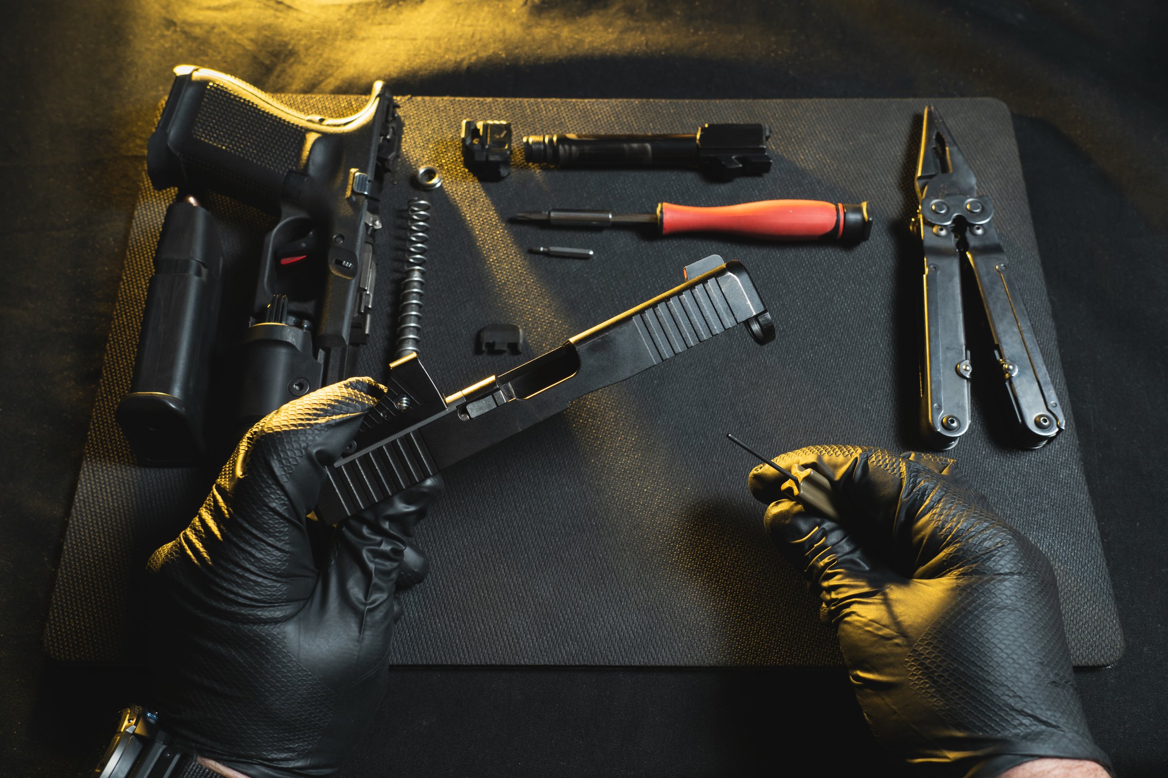 Cleaning and repairing weapons. Hands of a gunsmith and a disassembled pistol g19 in a workshop. Close up photo