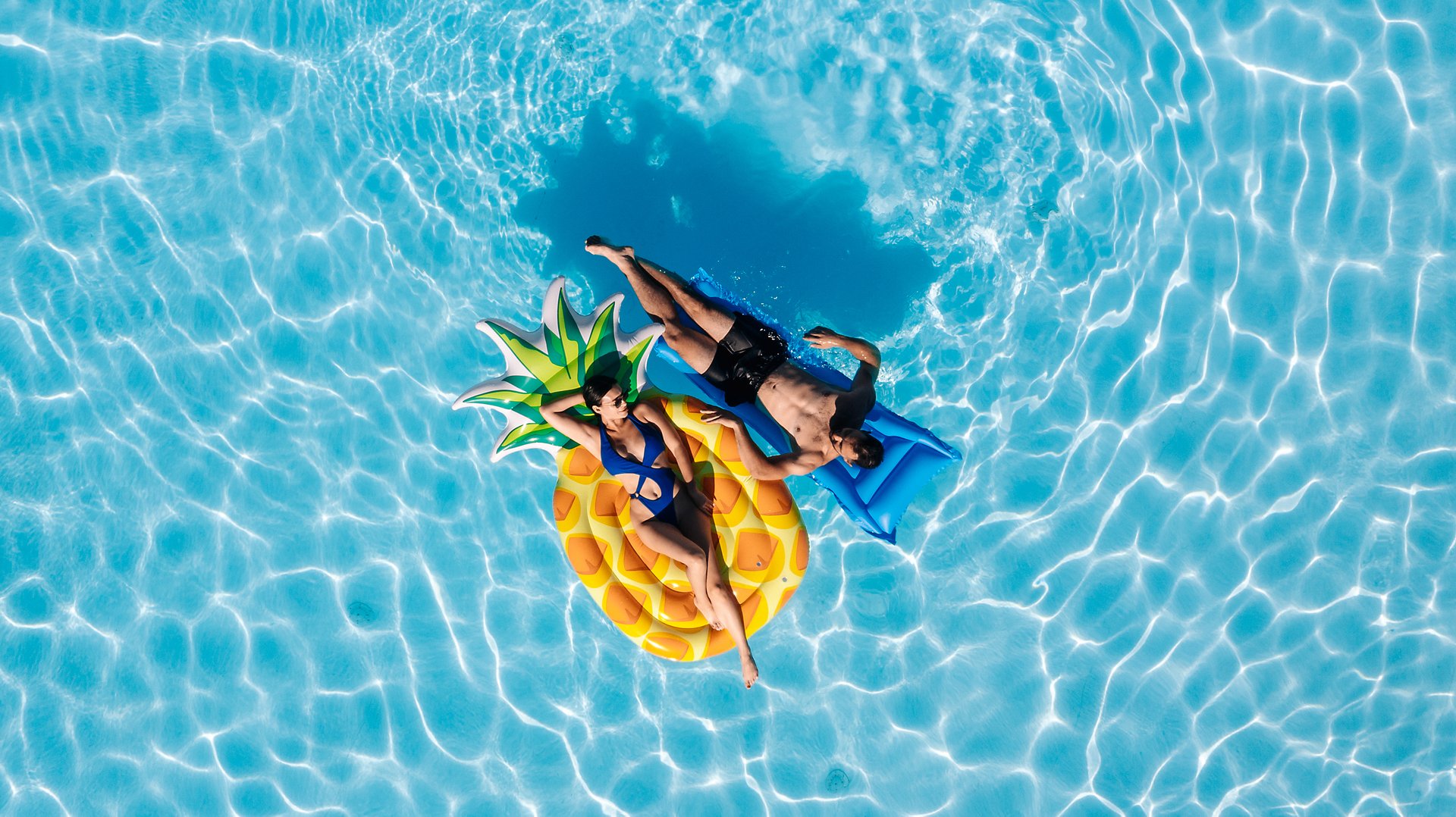 Young beautiful couple relaxing and enjoying vacation in the pool. Concept love, summer leisure, luxury, romance and tropical lifestyle.