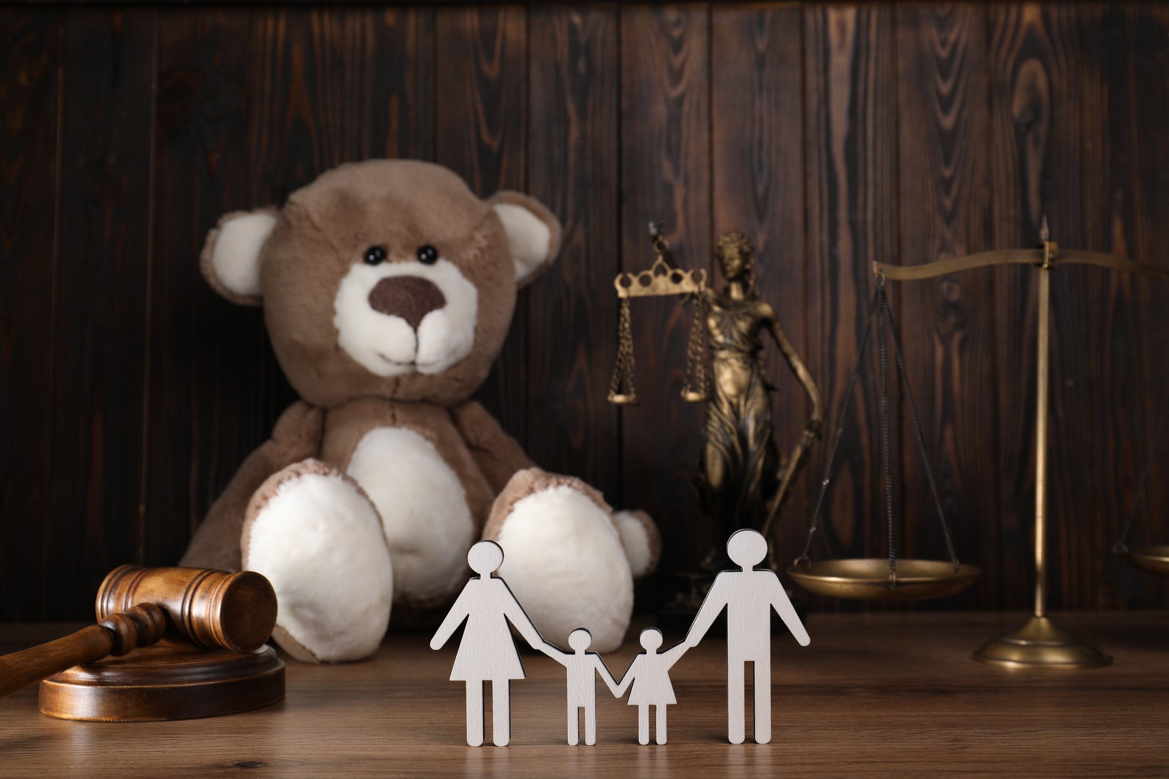 Alimony. Figures of family, gavel, toy bear, scales and statuette of Lady Justice on wooden table