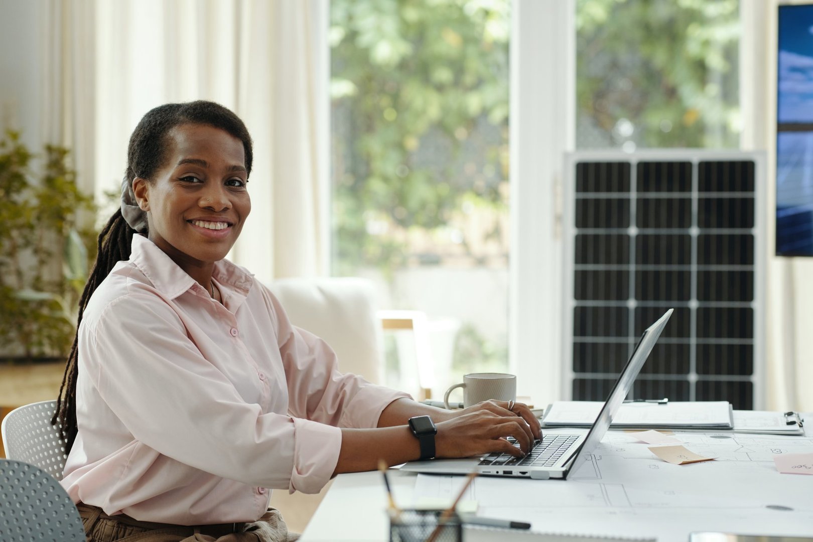Portrait of African American businesswoman smiling at camera while working on laptop in office