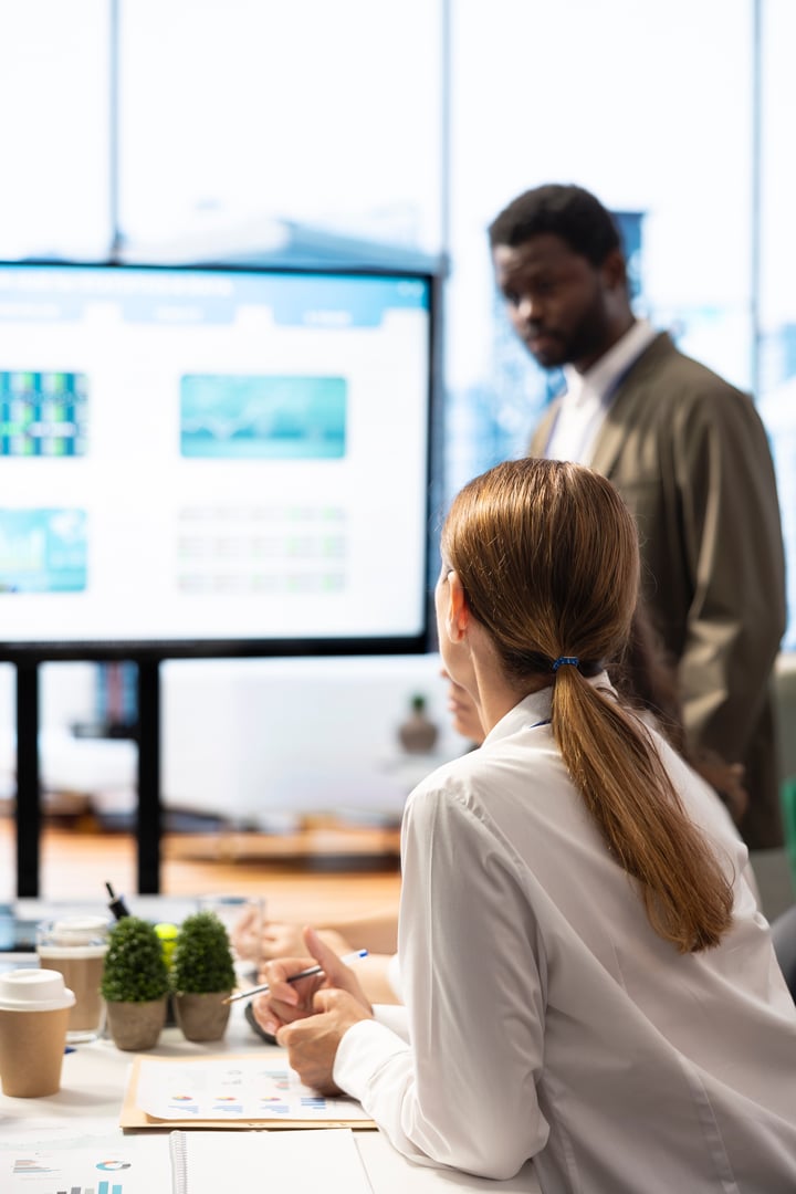 Business professionals engaging in a strategy session during meeting, utilizing an interactive board and data analytics to develop innovative solutions for global enterprise development.