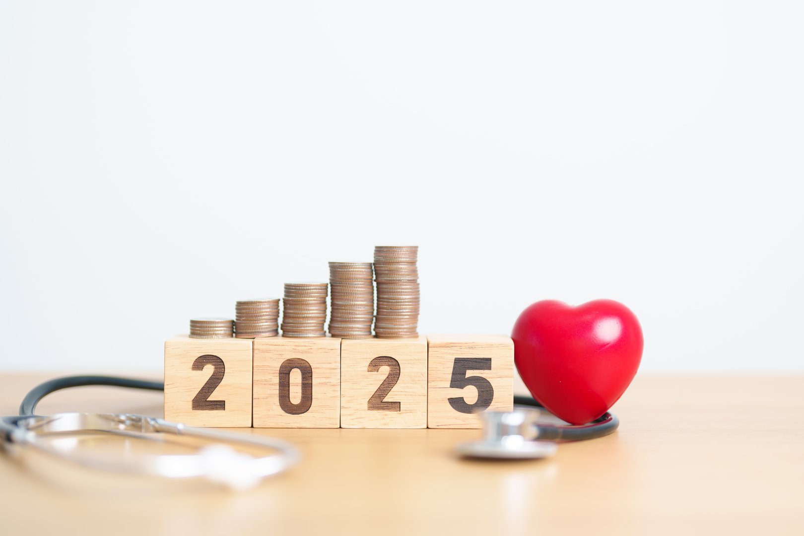 Happy New Year 2025 with doctor Stethoscope, coins stack and red heart on table. health care, Money saving, Goal, Resolution, health Insurance, Wellness and medical concept