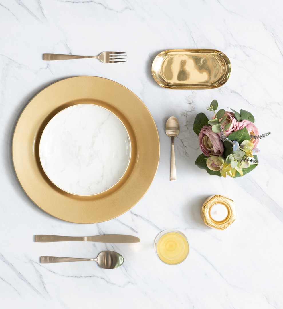 Capture the essence of luxury dining with this pristine tablescape. Gold accents, marble plate, and a beautiful floral centerpiece create an inviting atmosphere, perfect for celebratory meals.