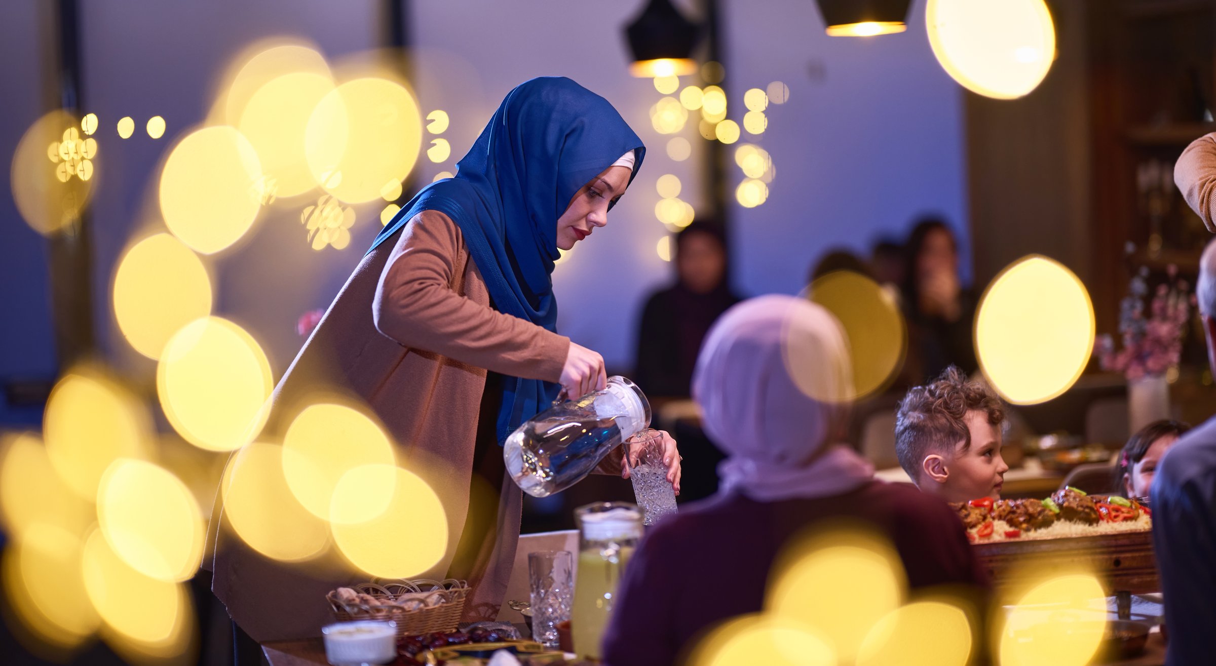A modern and traditional European Islamic family comes together for iftar in a contemporary restaurant during the Ramadan fasting period, embodying cultural harmony and familial unity amidst a culinary celebration of diversity.