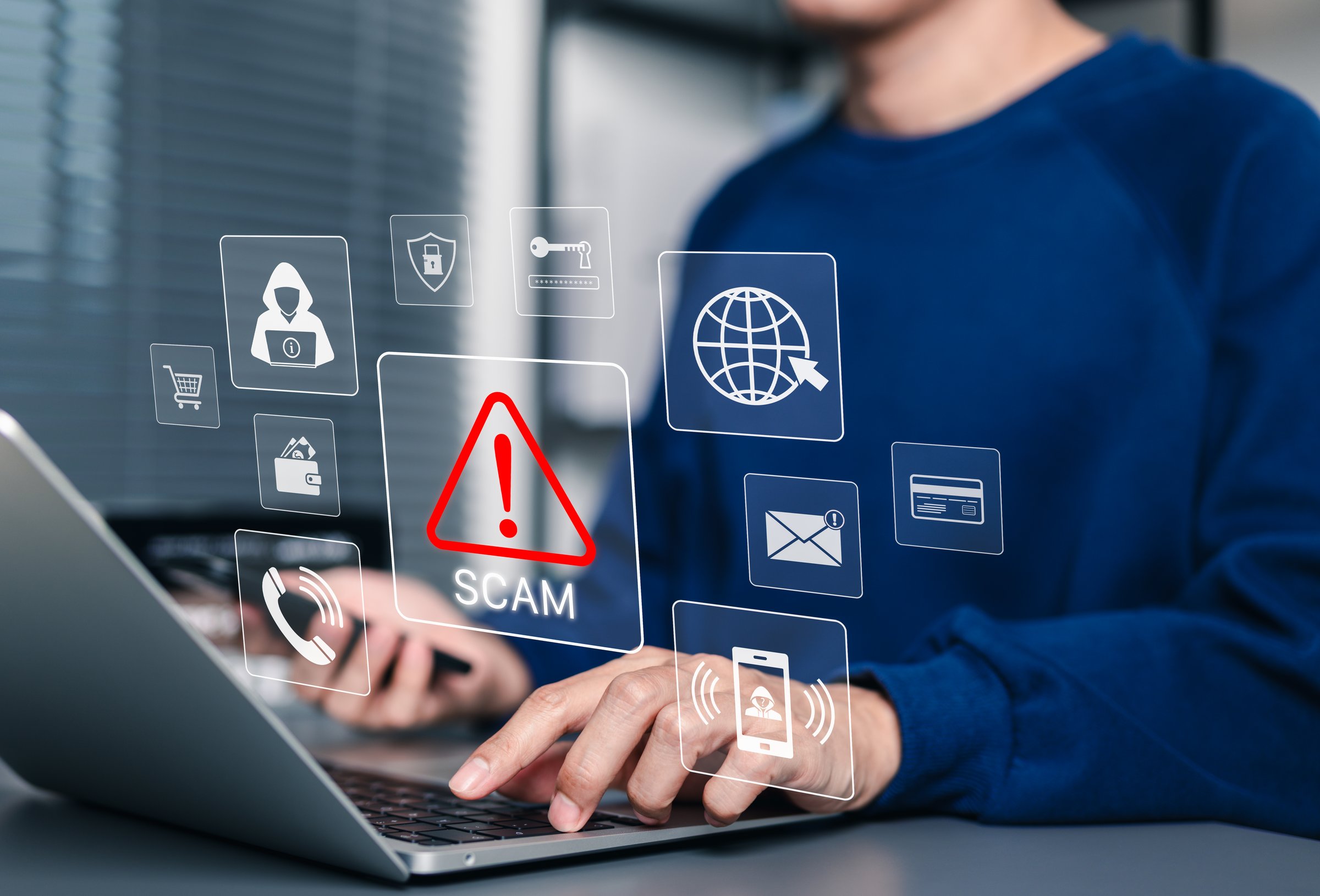 Scam Alert Warning with Cybersecurity Icons. Man holding smartphone while using laptop, warning sign for scams with icons online threats, phishing, cybersecurity, Unknown person, suspicious scammer