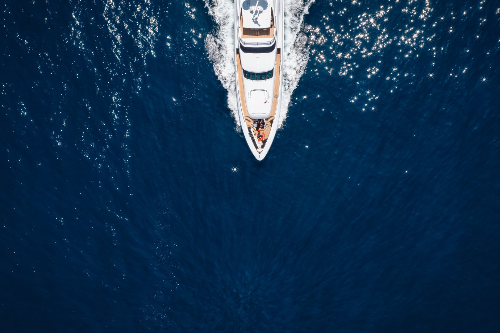 Aerial overhead view of a bow of a luxury yacht cruising with speed over ocean with copy space