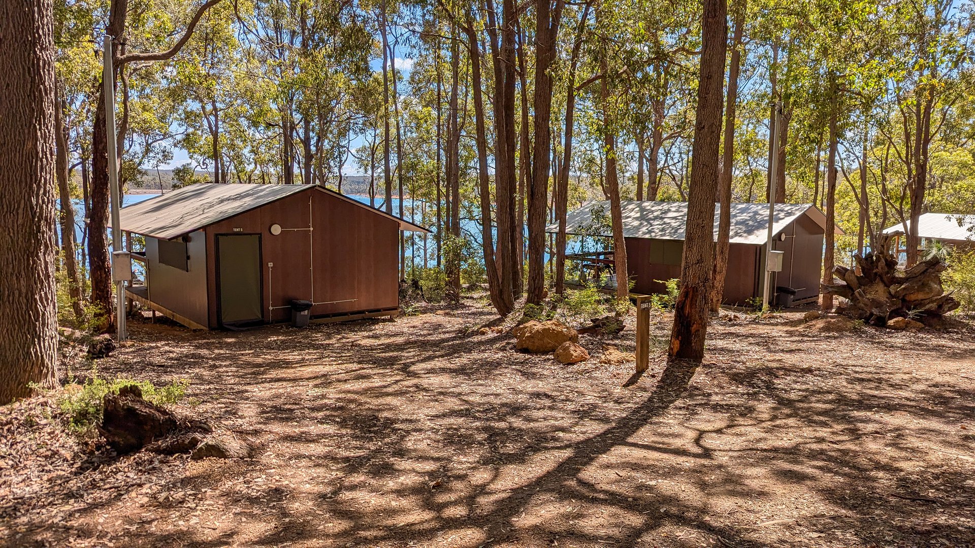 Tranquil lakeside cabins surrounded by lush forest in Western Australia. Ideal for nature lovers seeking serene retreats, outdoor adventures, and camping escapes. Travel stock photography.