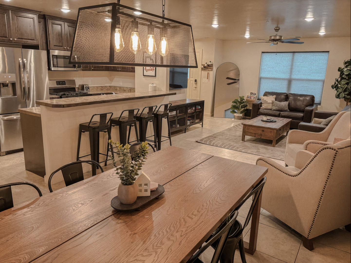 Modern open-concept living area with a kitchen island, dining table, and cozy seating area with a couch and armchair.