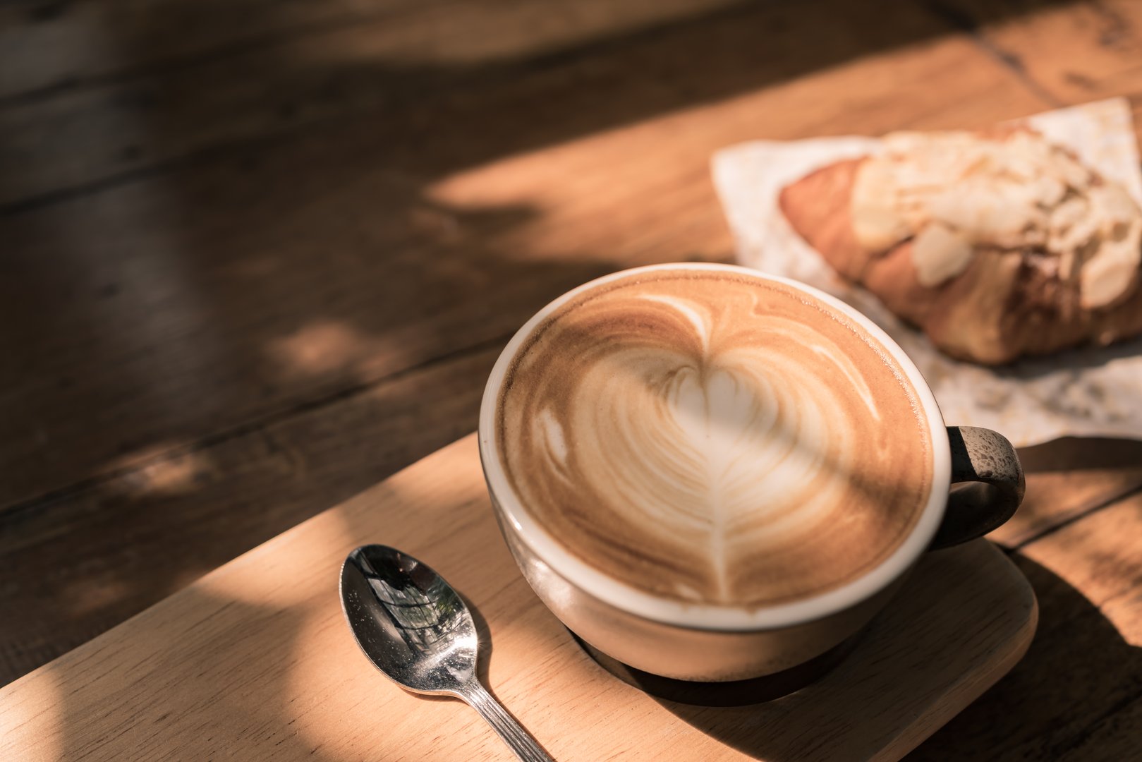 Hot Coffee cup and fresh baked croissant on wooden background.