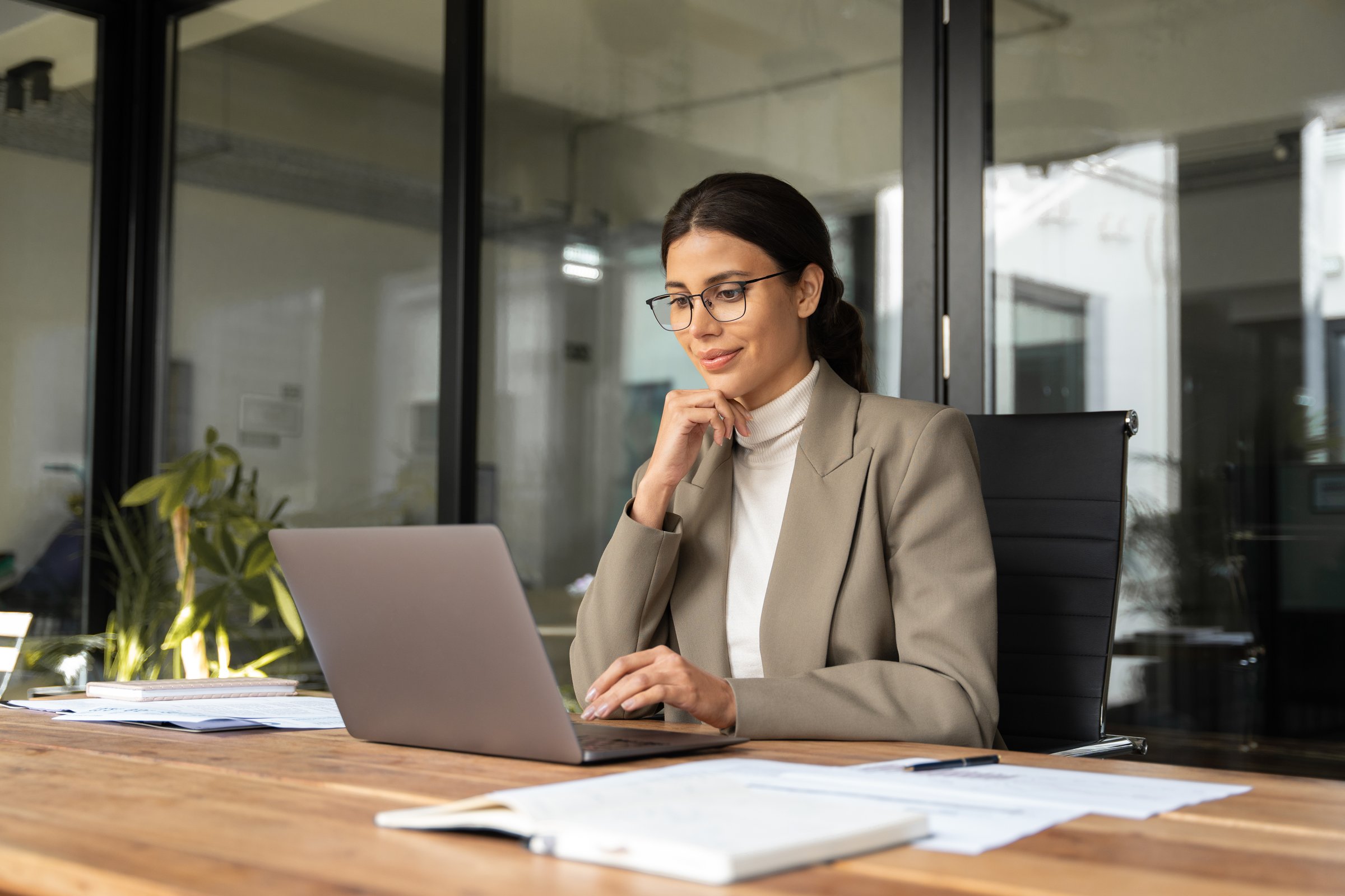 Focused professional financial it specialist latin hispanic business lady working concentrated on laptop pc sitting in office. Middle eastern indian woman using computer technology app for work online