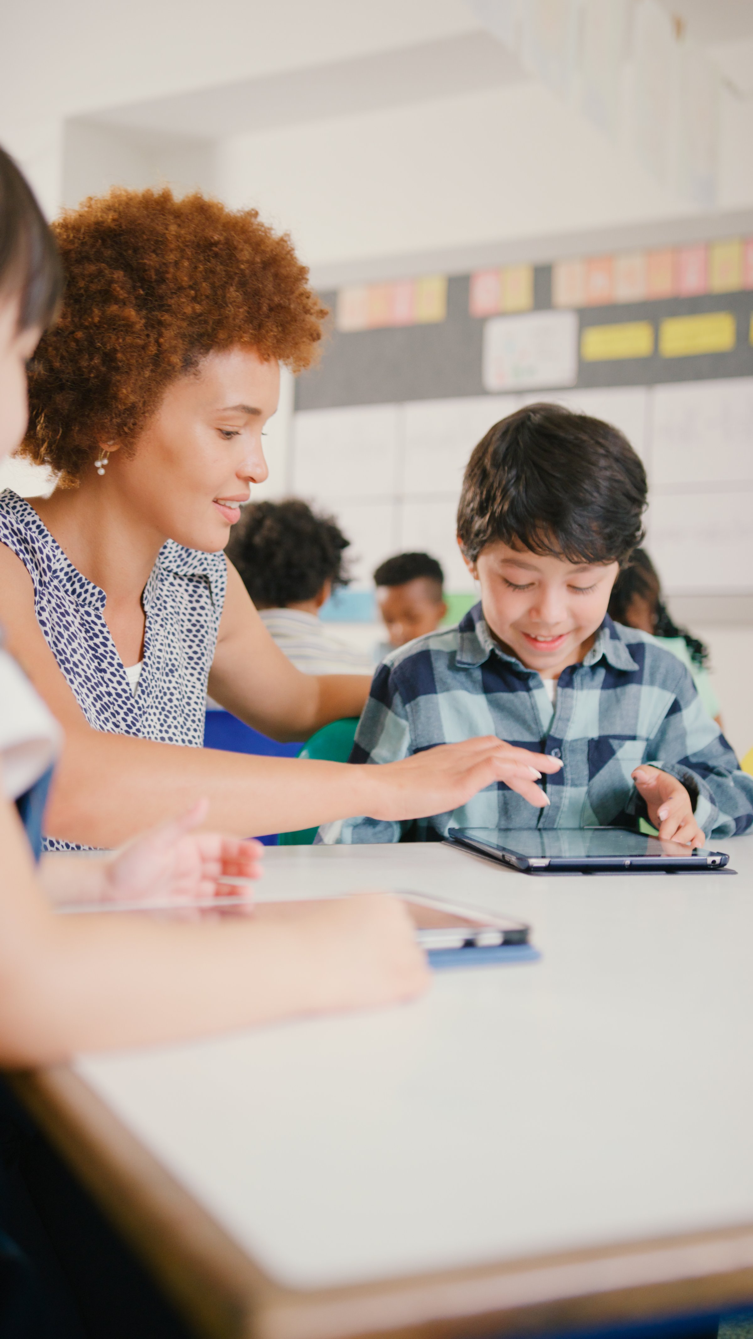 Female Teacher With Elementary School Students Using Digital Tablet In STEM Class