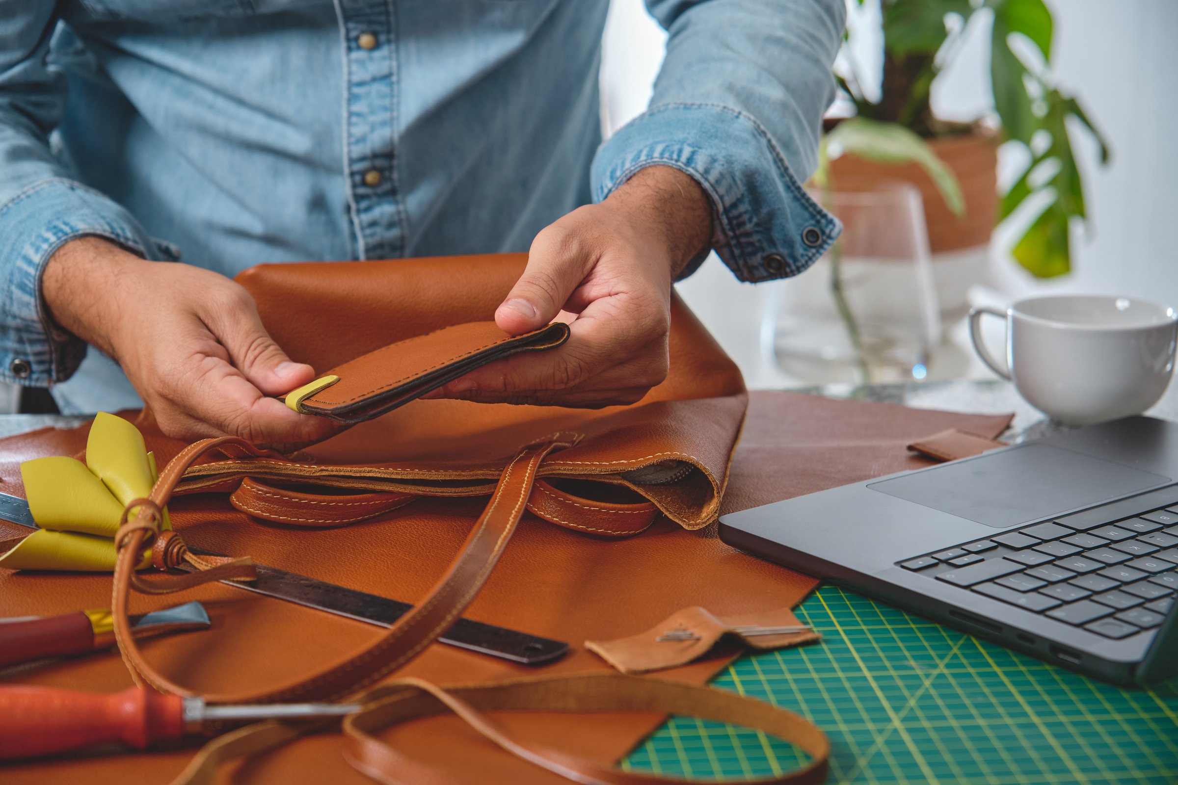 Craftsman inserting a pocket into a leather bag, working in his workshop