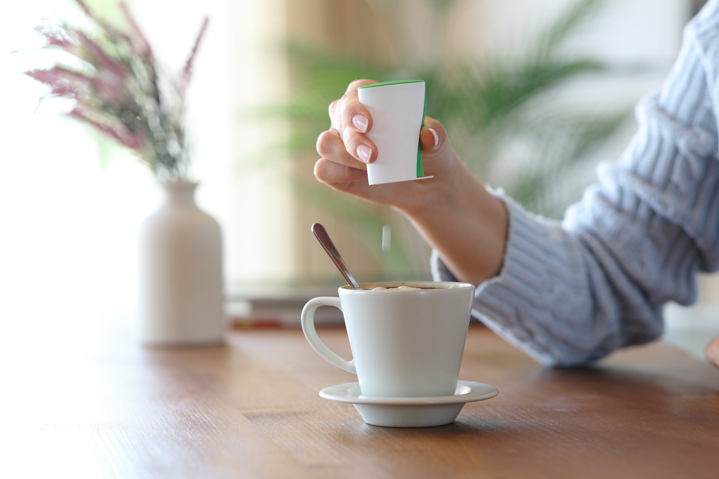 Close up of a woman hand throwing saccharin pill on coffee cup at home