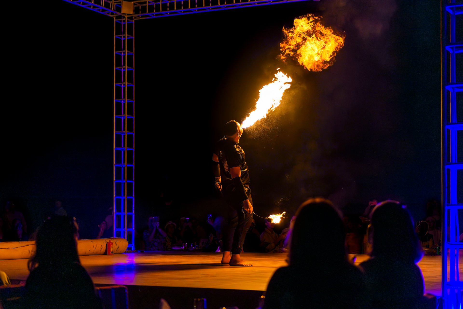 A fire performer blows flames out of his mouth on stage at an outdoor arena at night in the Sharjah desert of Dubai, United Arab Emirates.