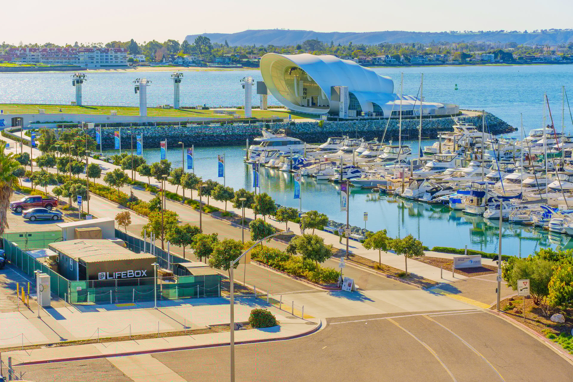San Diego, California - January 14, 2025: Scenic view of Rady Shell at Jacobs Park in San Diego, California, showcasing the marina filled with boats and vibrant greenery under clear skies.