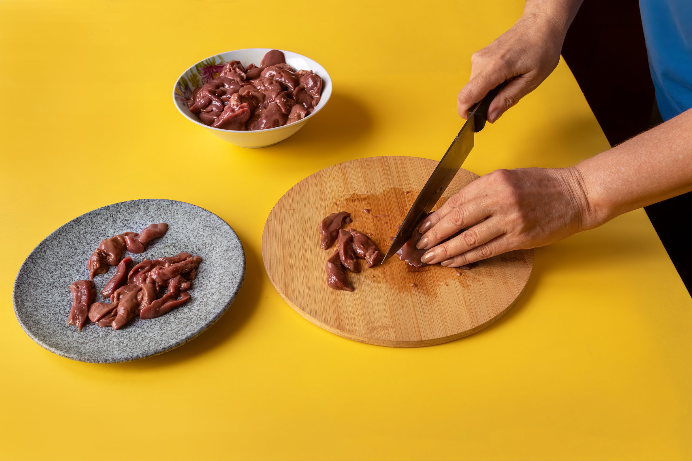 Close-up of housewife's hands while cutting chicken liver.