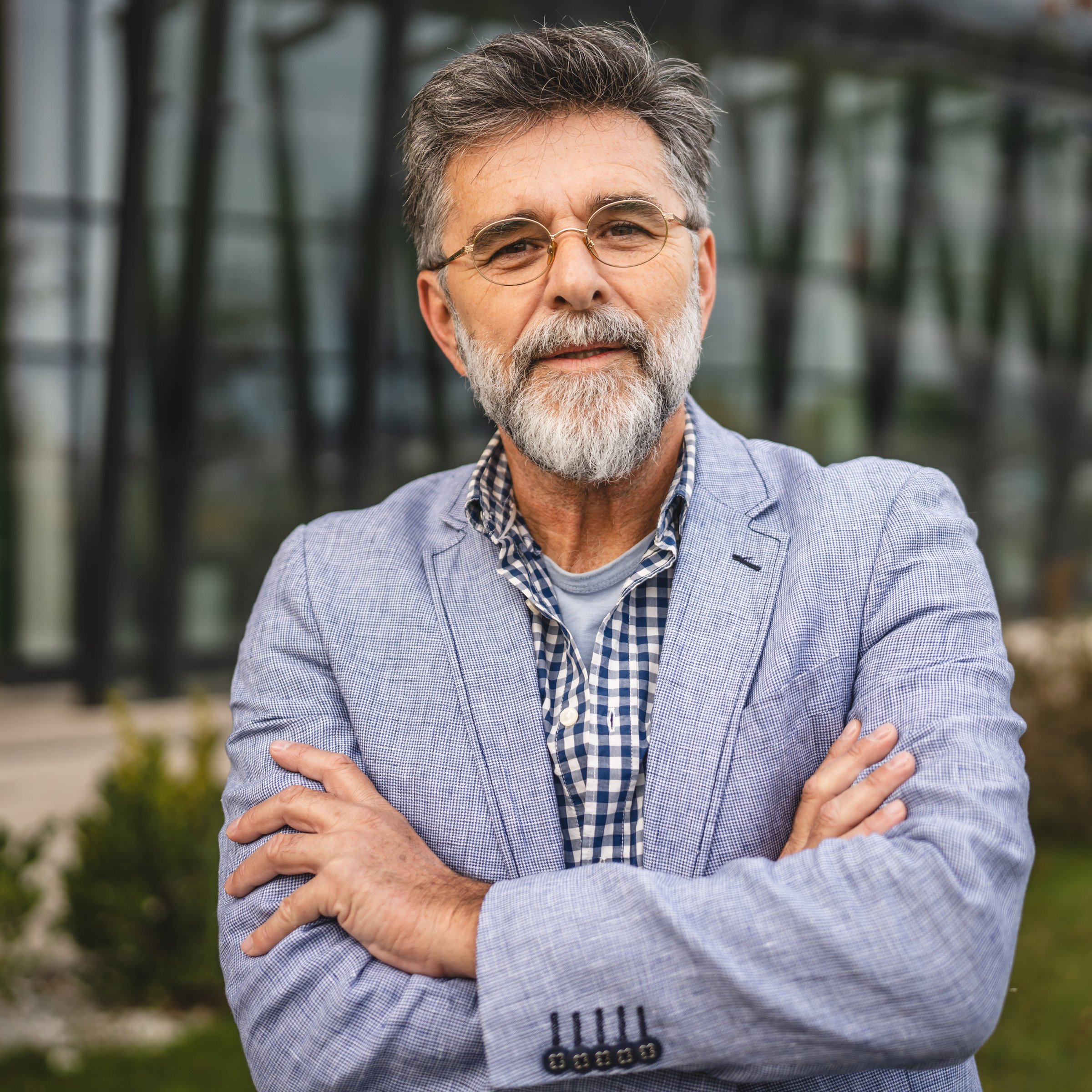 Portrait of senior man businessman arm crossed in front modern building