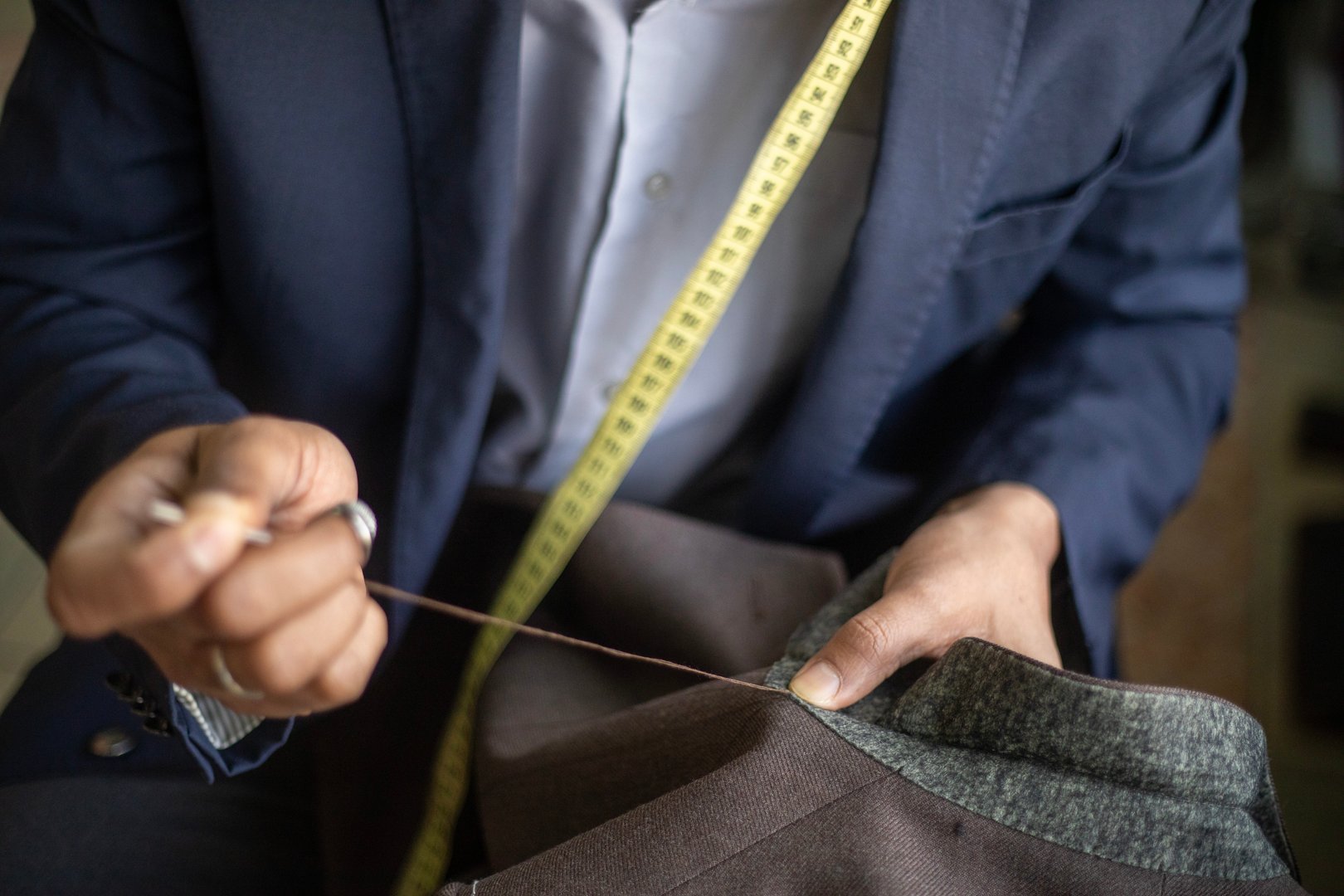 Bespoke tailor hand stitching the under collar to a traditionally made jacket