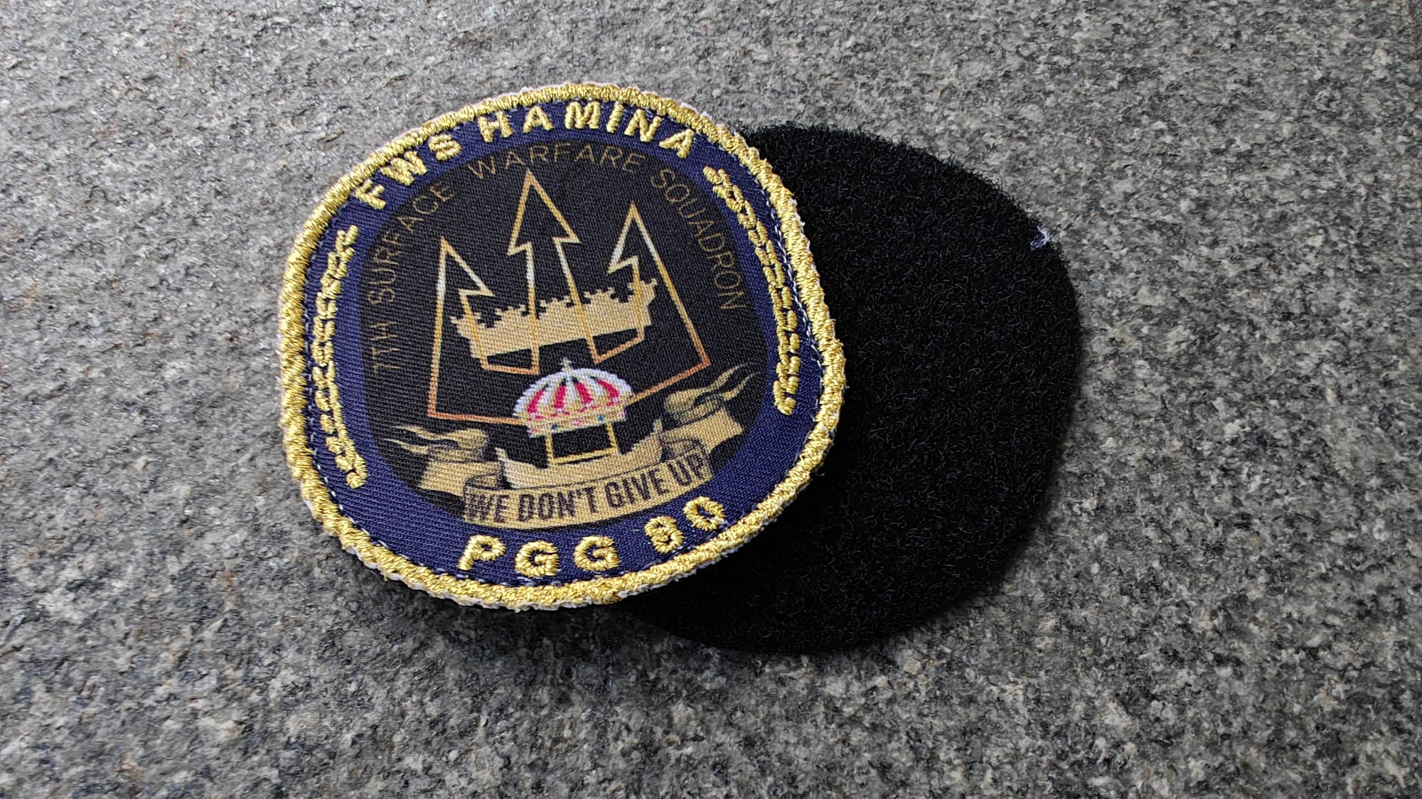 Patch of FNS Haminas with Surface Warfare Squadron and motto We Don’t Give Up. Features a trident emblem, PGG 90.
