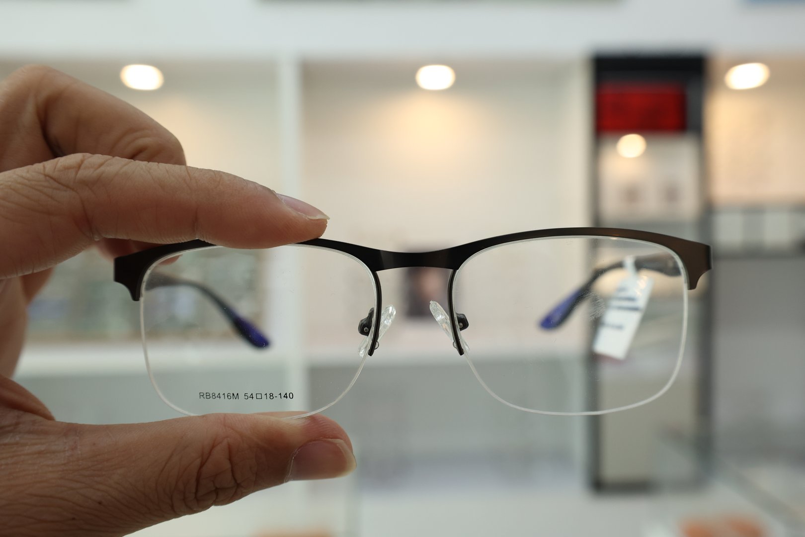 Hand holding eyeglasses in optical store