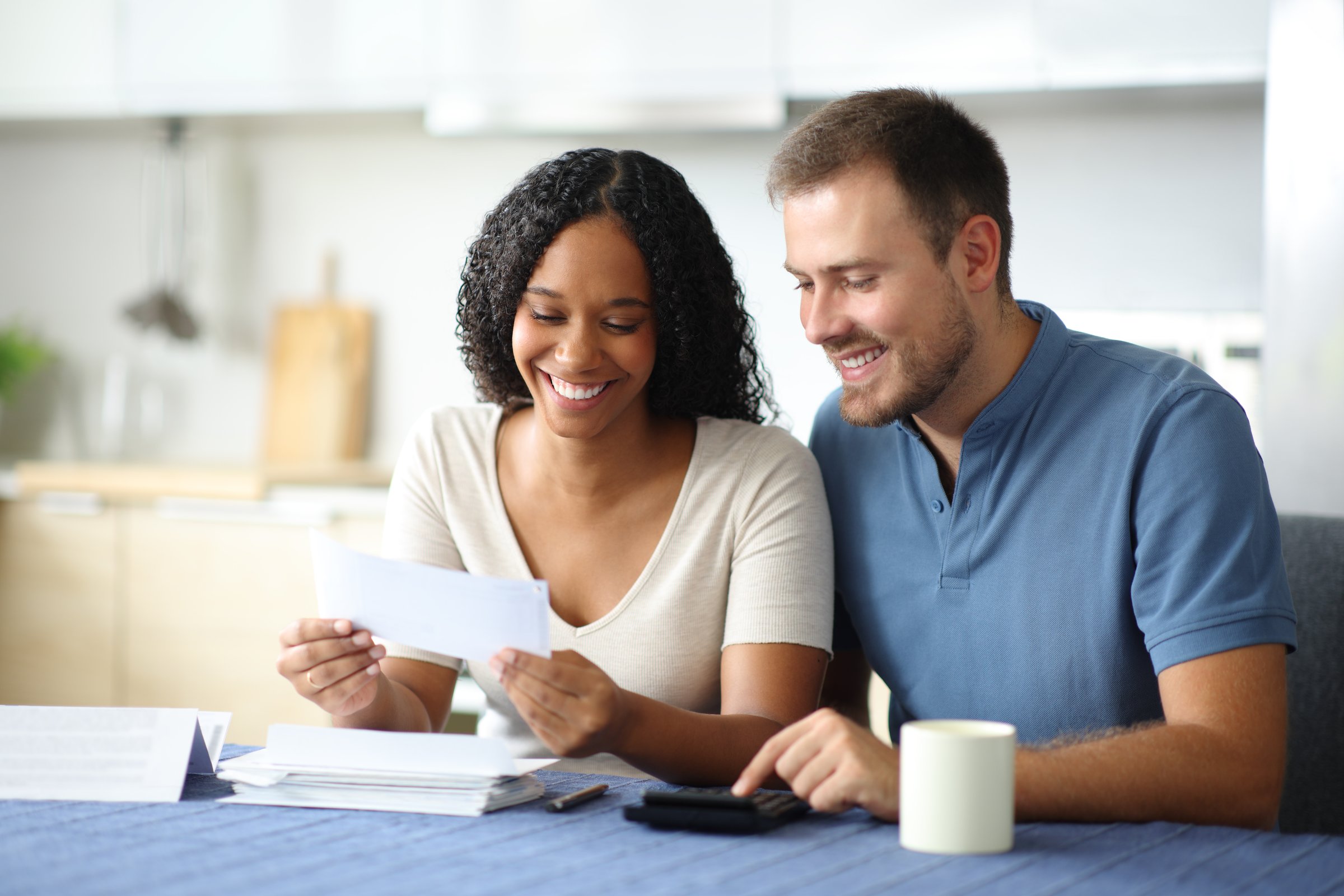 Happy couple reading bank statement in the kitchen at home