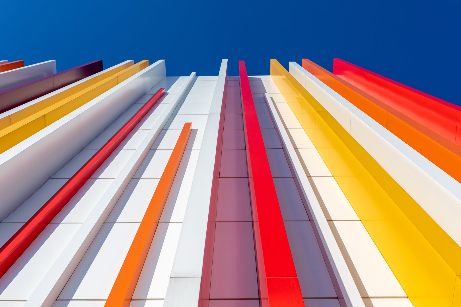 a fragment of a wall decorated with multicolored plastic on a blue sky background. Vertical perspective