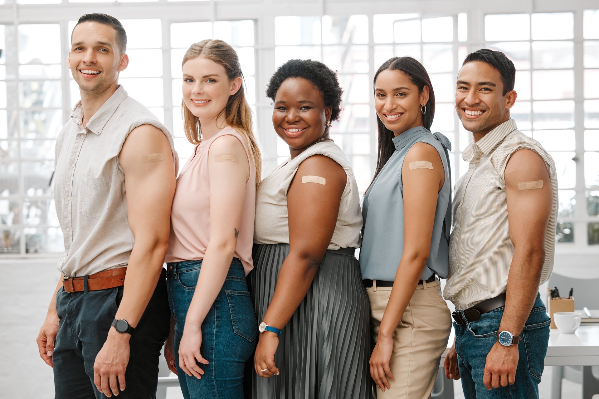Covid vaccine, safety and health colleagues with plaster after vaccination for business protocol or policy and protection against the virus. Smiling faces of worker standing together, showing support