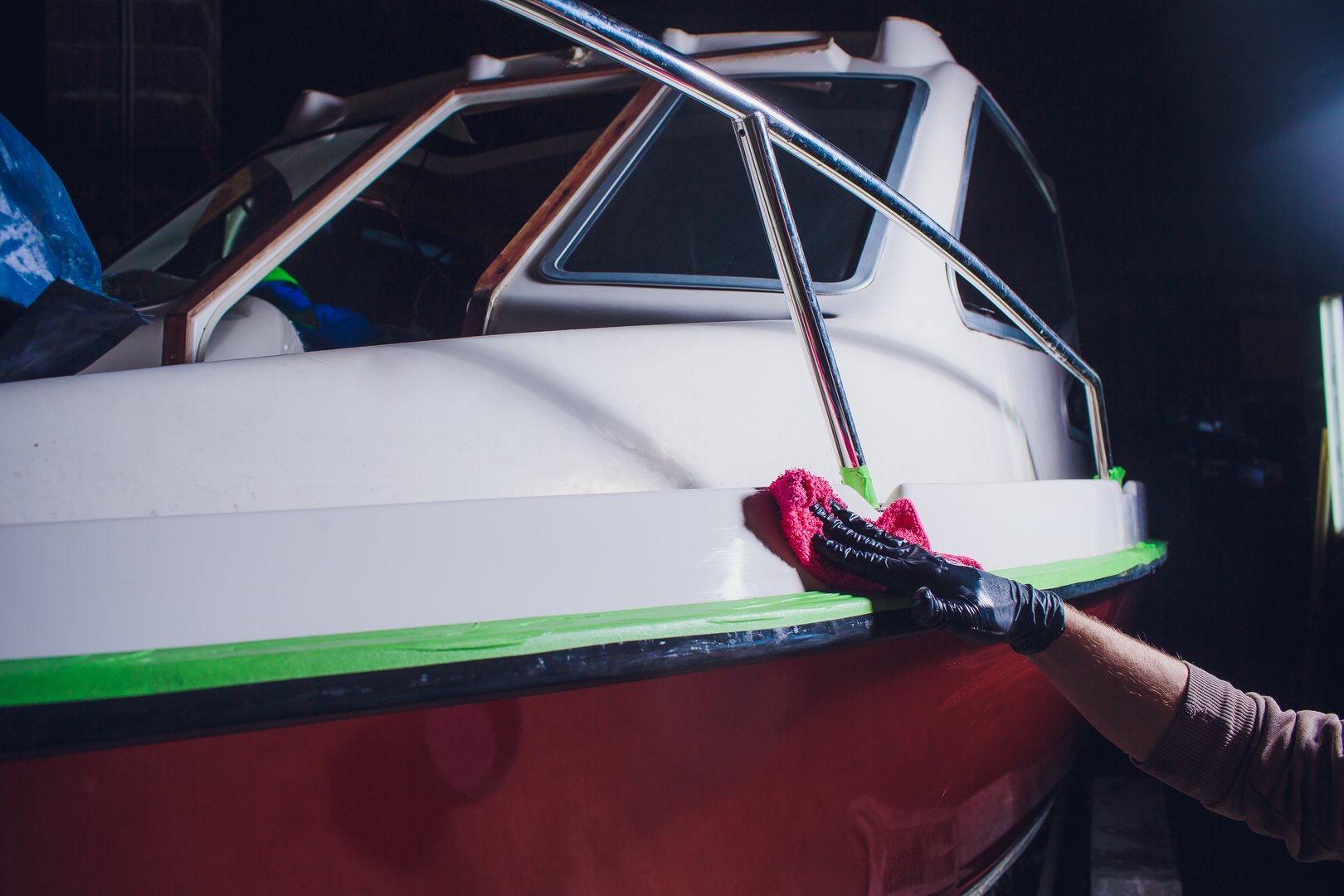 A man washes the deck of the yacht with a pink rag. preparation in polishing, repair of yacht, boat