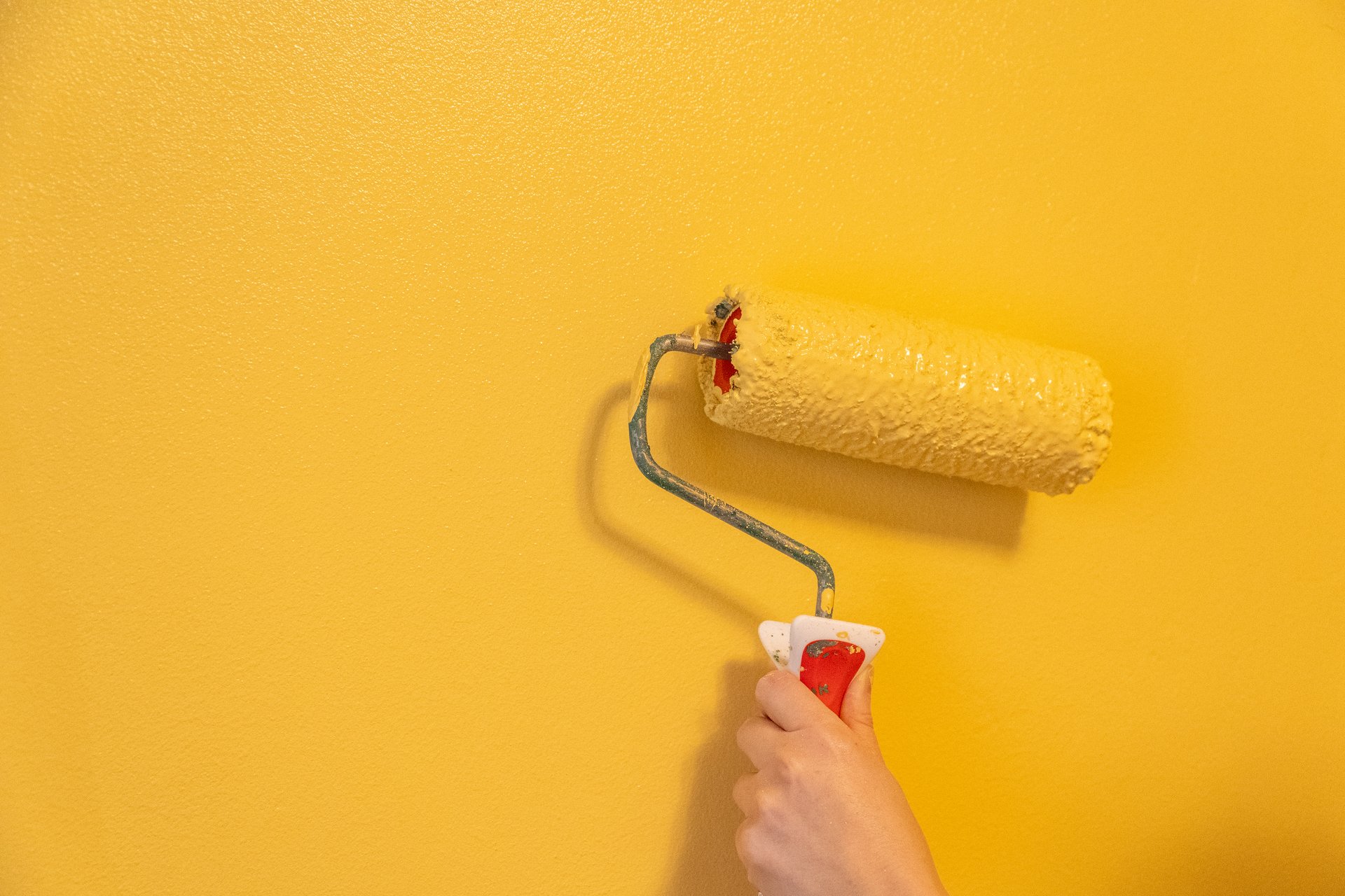 Roller Brush Painting. Worker painting on surface wall Painting apartment, renovating with yellow color paint.